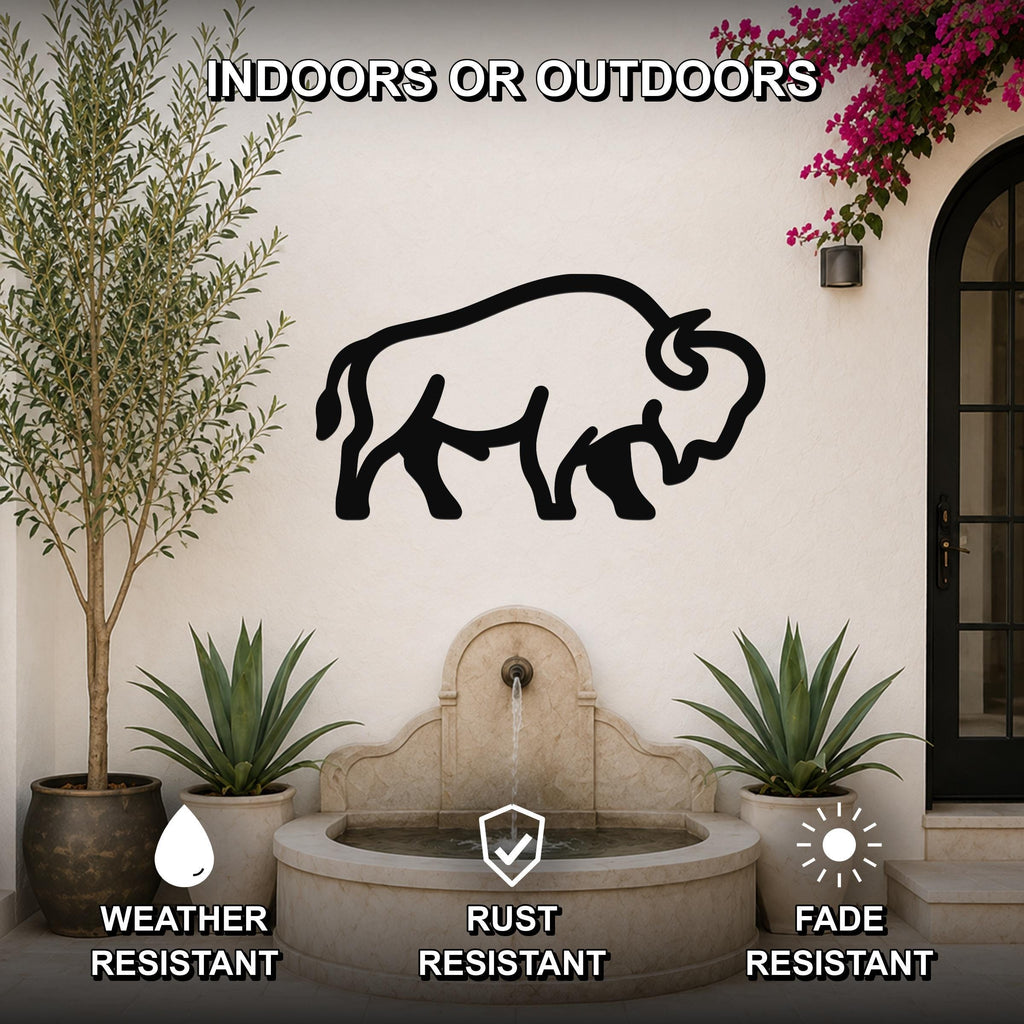 Black metal bison silhouette wall art mounted on an outdoor stucco wall above a stone fountain, flanked by potted plants and a flowering vine.