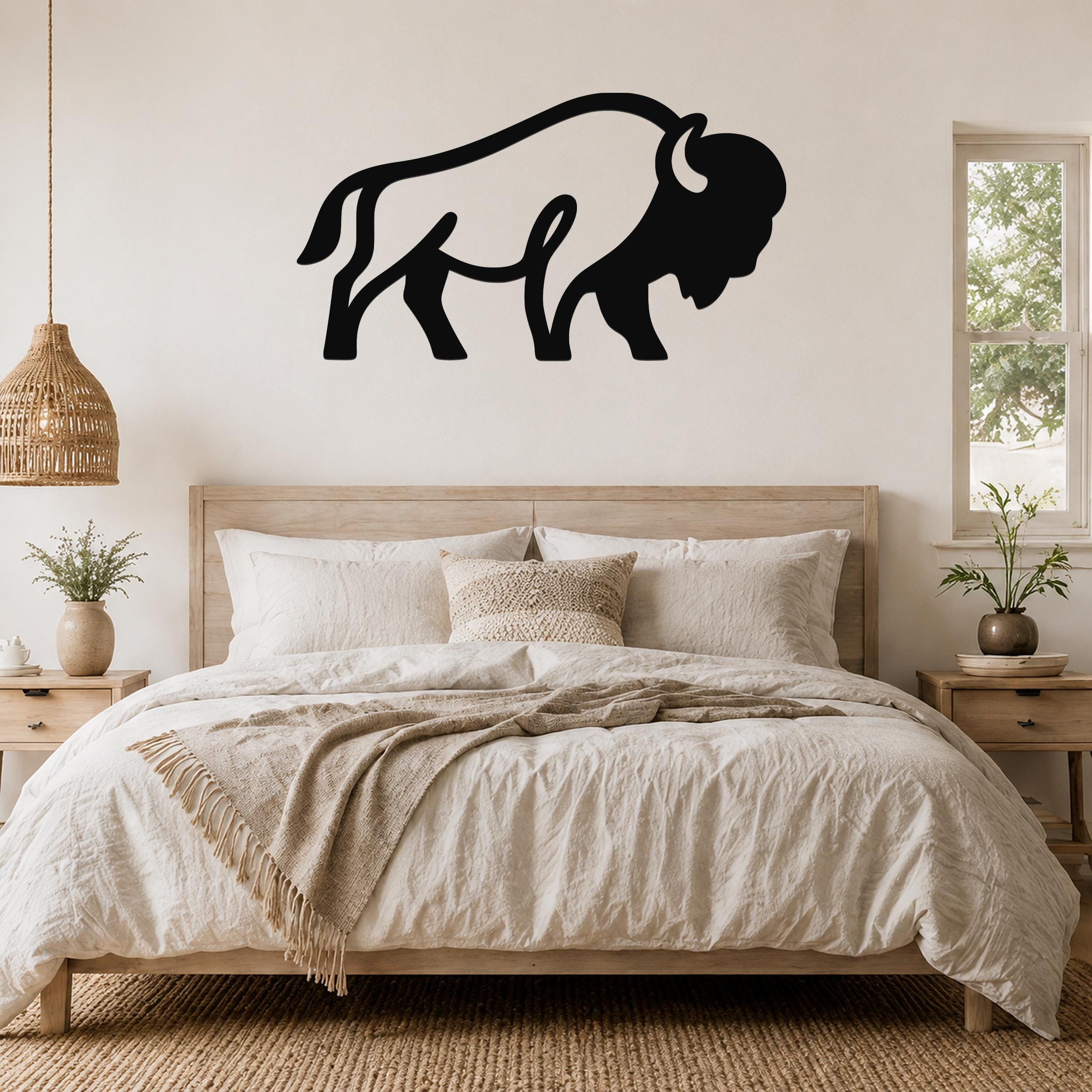 Black metal bison silhouette wall art mounted above a wooden bed in a neutral bedroom.