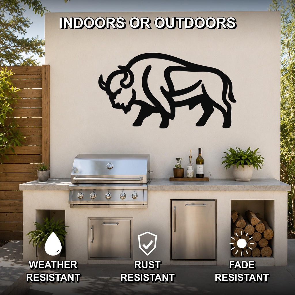 Black metal bison silhouette wall art mounted on an outdoor kitchen wall above a grill, with visible cutout details and a rustic patio setting.
