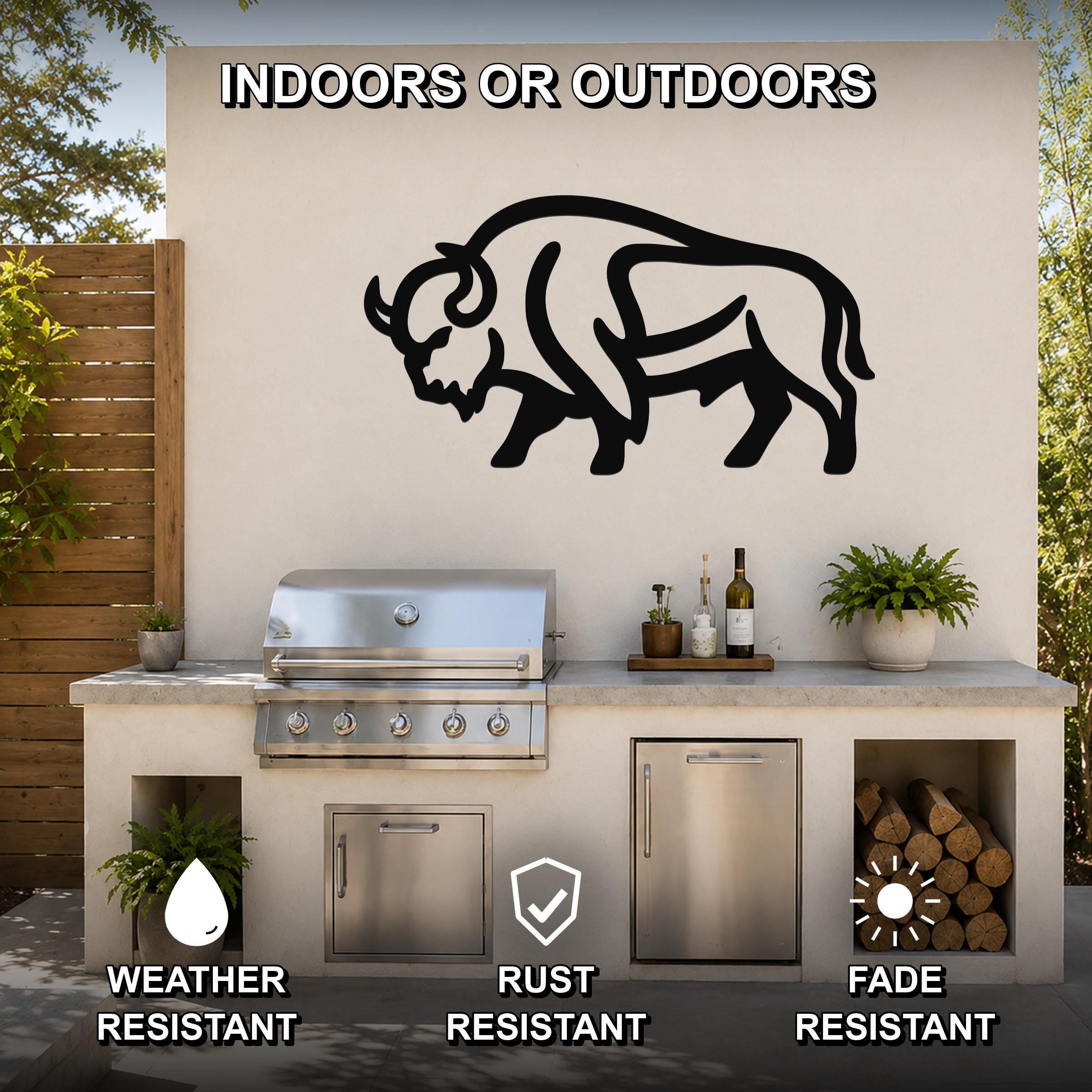 Black metal bison silhouette wall art mounted on an outdoor kitchen wall above a grill, with visible cutout details and a rustic patio setting.