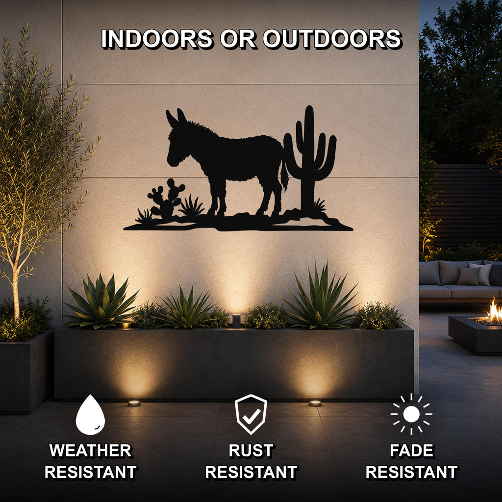 Black metal wall art featuring a burro silhouette with cacti, mounted on an outdoor wall above a planter in a patio setting.