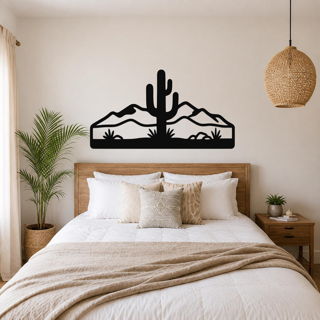 Black metal wall art featuring a saguaro cactus and mountain silhouette, mounted above a bed in a bedroom.