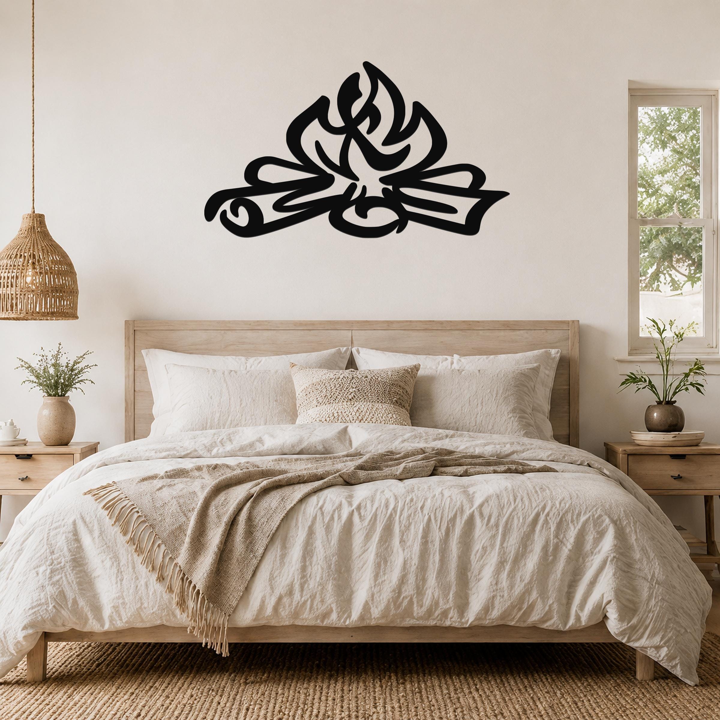Black metal wall art with a flame silhouette design, mounted above a bed in a rustic bedroom.