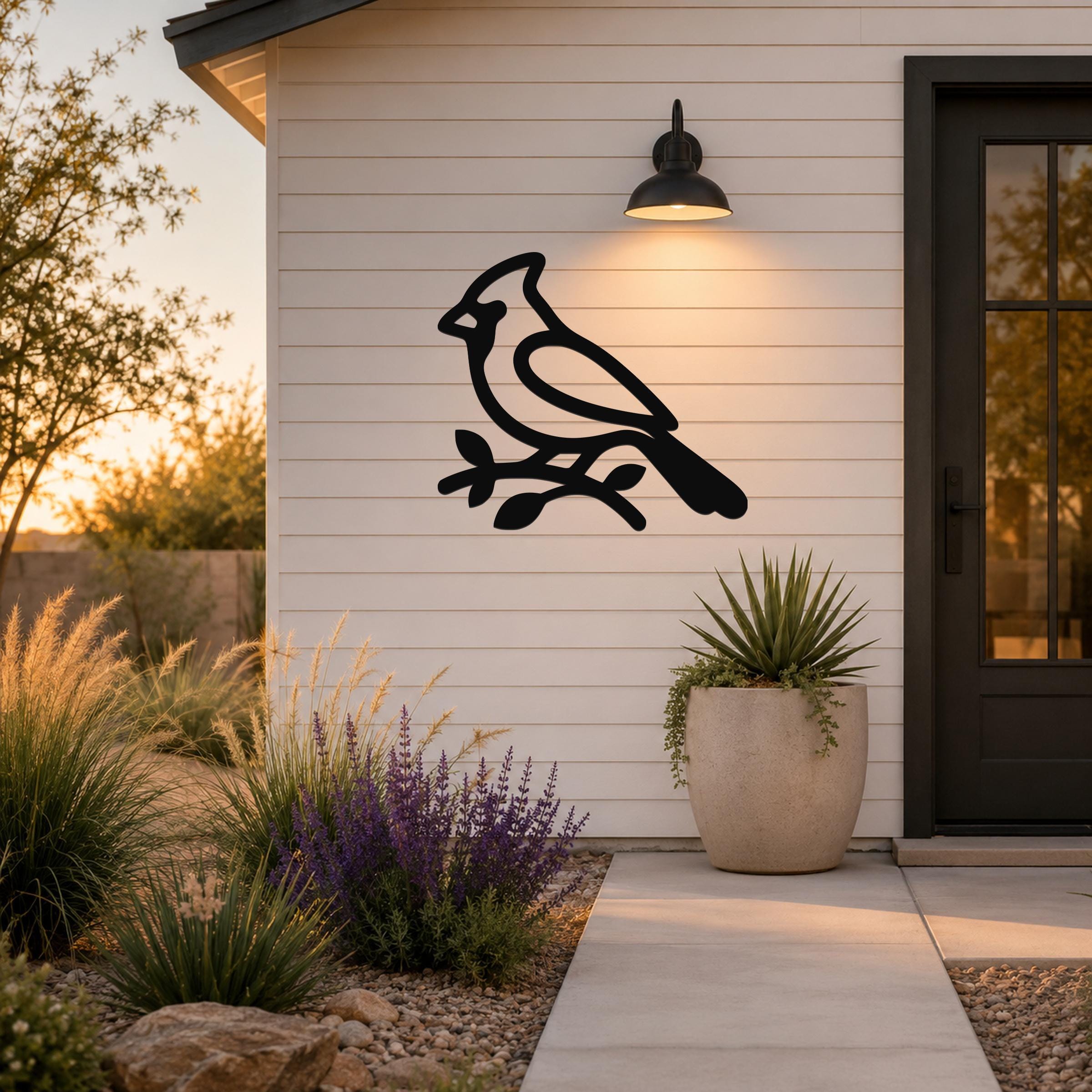Black metal cardinal wall art silhouette perched on a branch, mounted on a white shiplap exterior wall above a patio entrance.