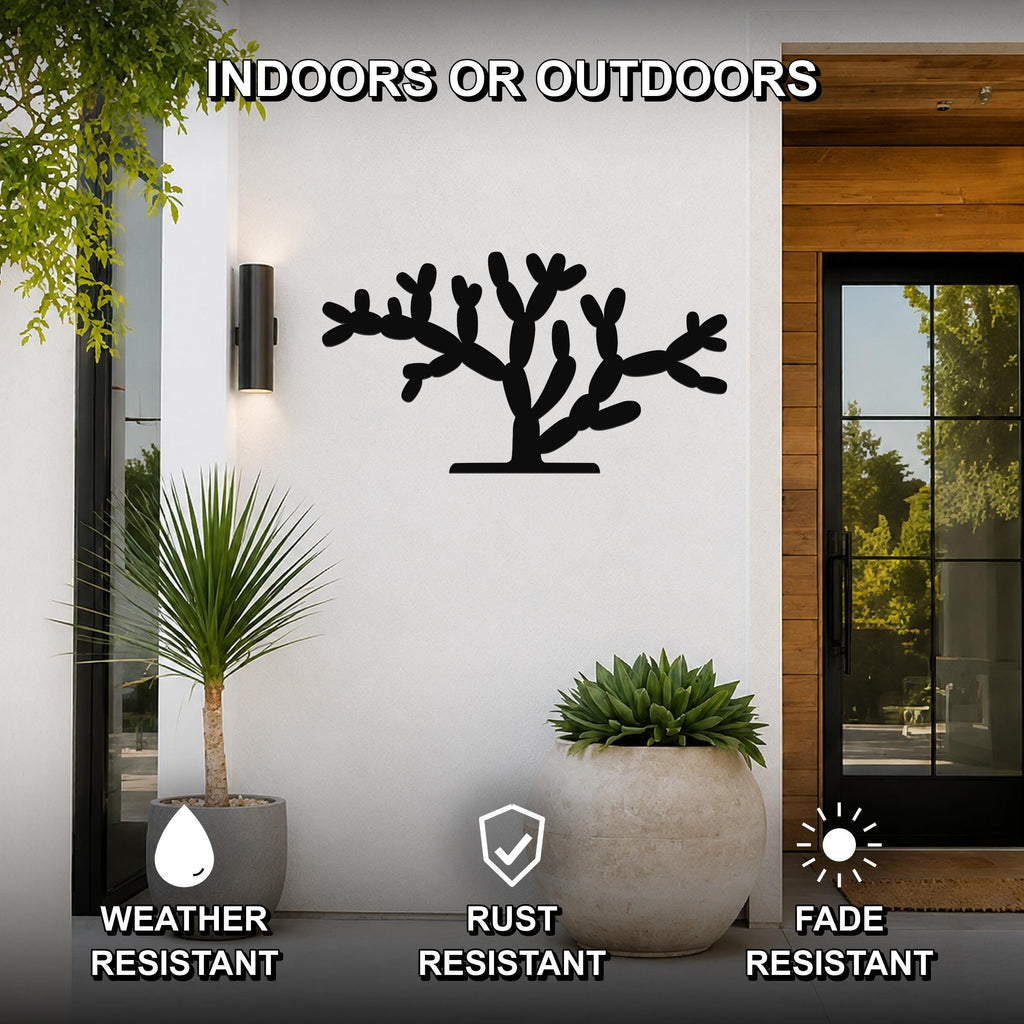 Black metal Cholla cactus wall art with branching cutouts, mounted on a white exterior wall beside a glass door and potted plants.