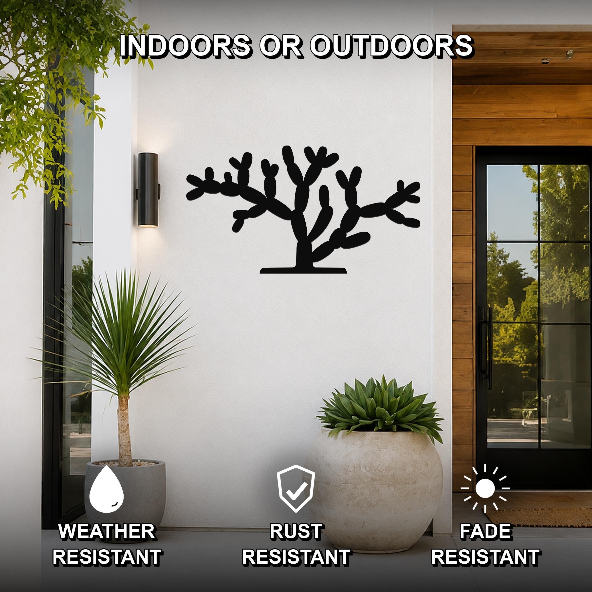 Black metal Cholla cactus wall art with branching cutouts, mounted on a white exterior wall beside a glass door and potted plants.