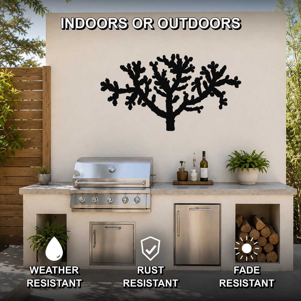 Black metal Cholla cactus wall art with branching cutout design, mounted on an outdoor kitchen wall above a stainless steel grill.