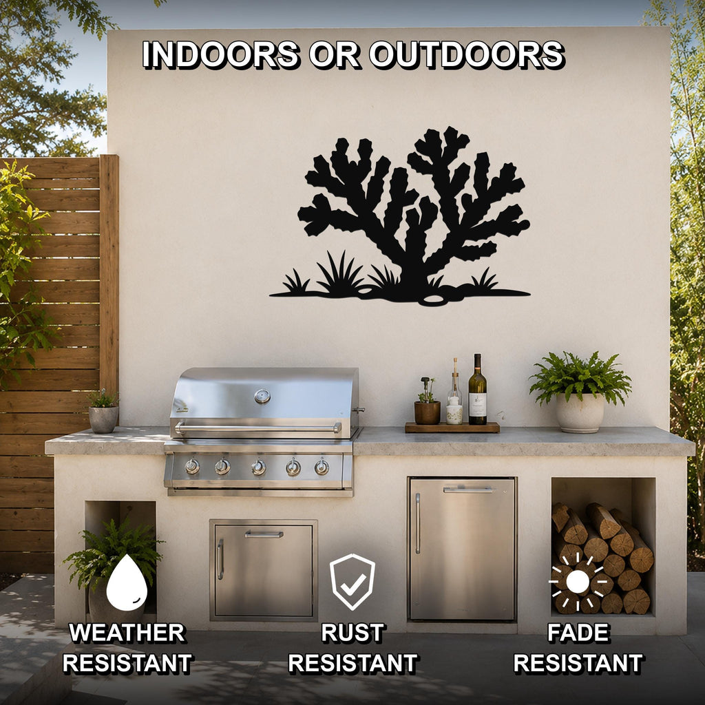 Black metal Cholla cactus wall art with branching silhouette and grass cutouts, mounted on an outdoor patio wall above a stainless steel grill and counter.