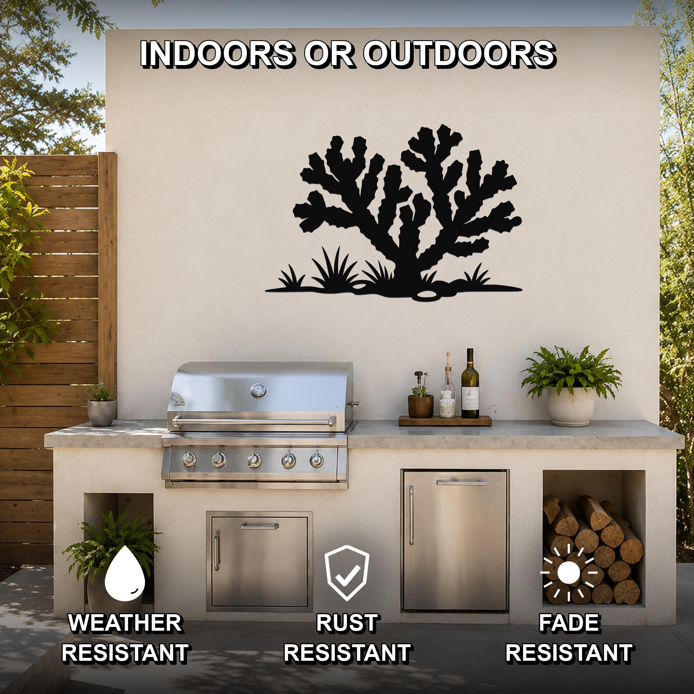 Black metal Cholla cactus wall art with branching silhouette and grass cutouts, mounted on an outdoor patio wall above a stainless steel grill and counter.