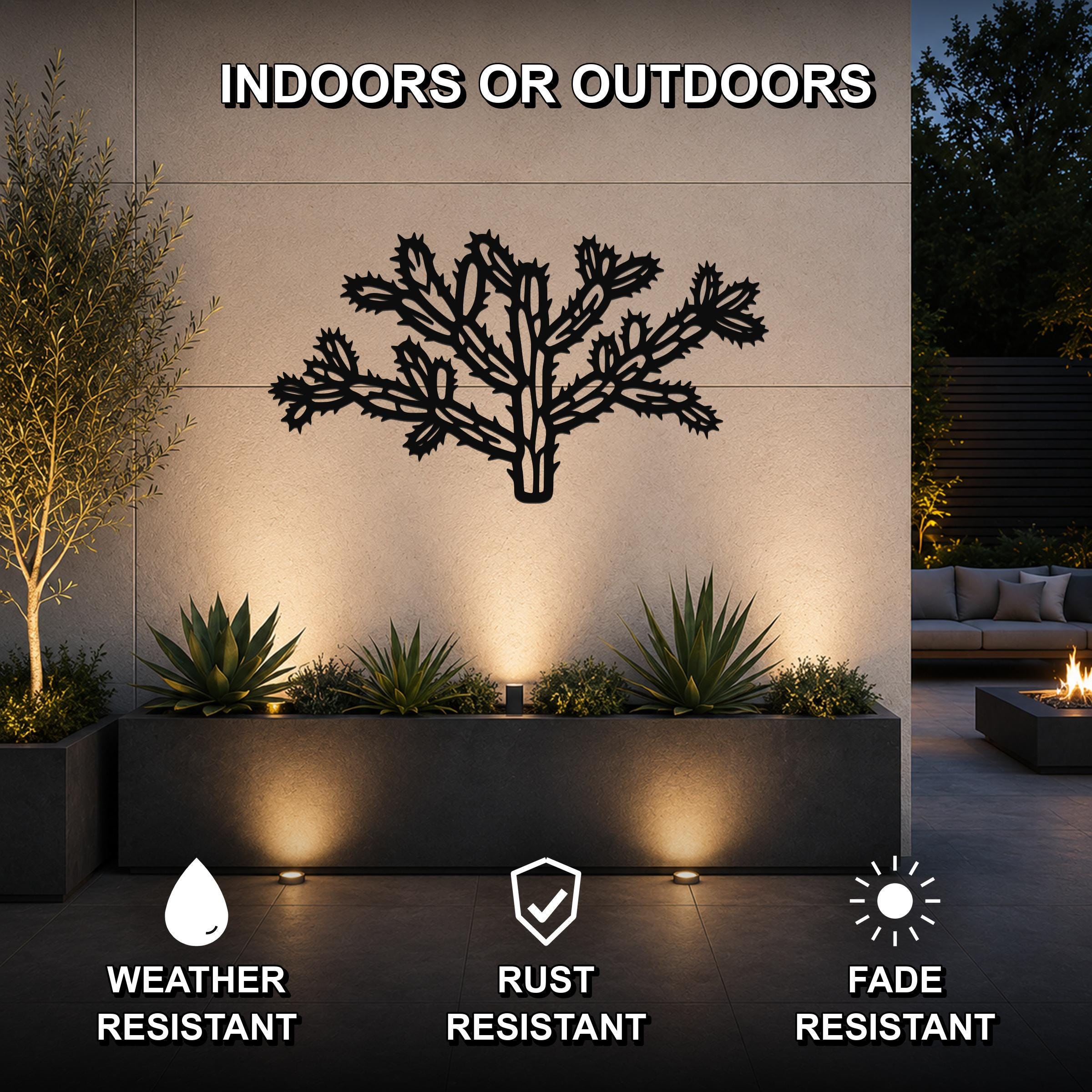 Black metal Cholla cactus wall art with detailed branch cutouts, mounted on an outdoor wall above a planter in a modern patio setting.