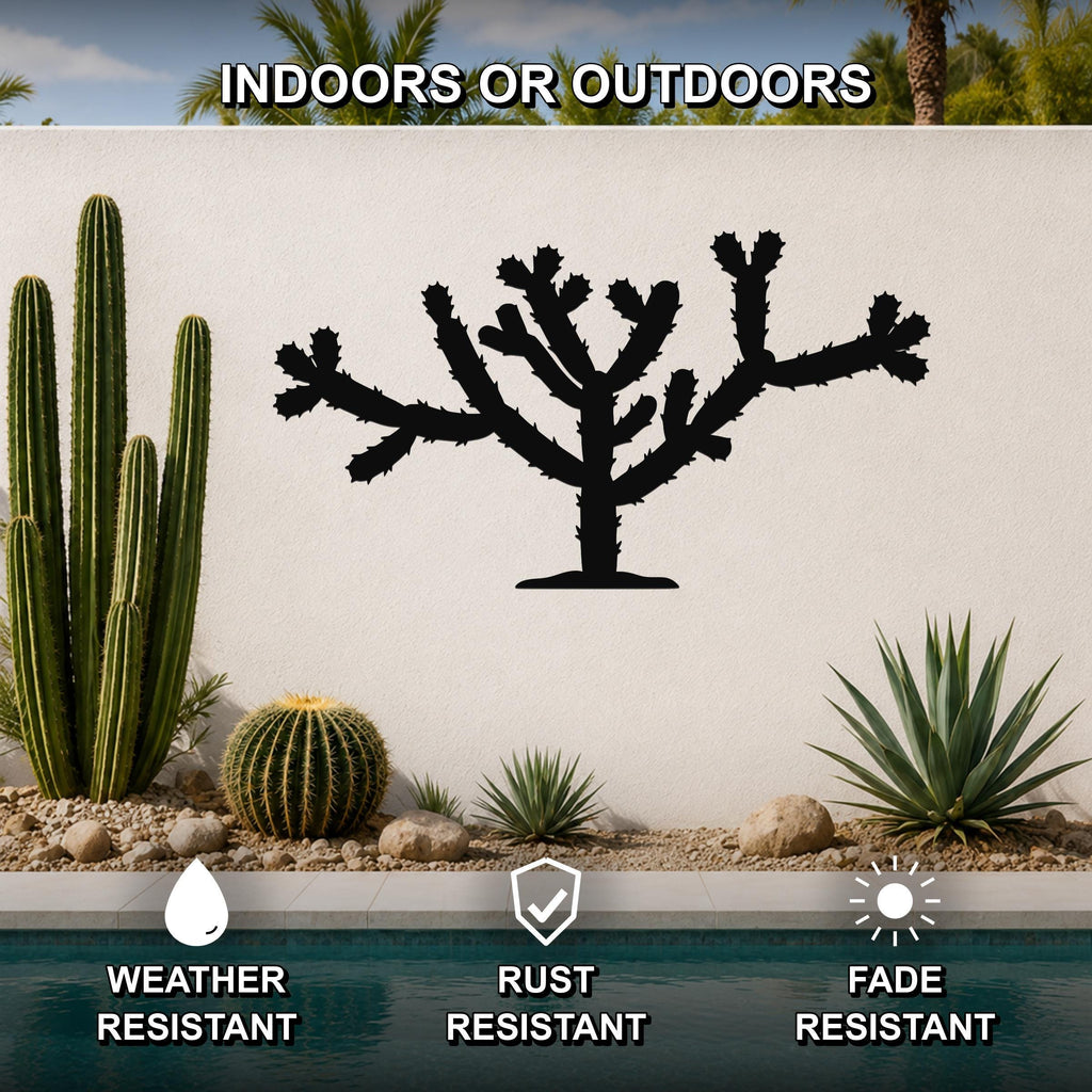 Black metal Cholla cactus wall art silhouette with branching arms and spines, mounted on a white outdoor wall above a pool in a desert garden setting.