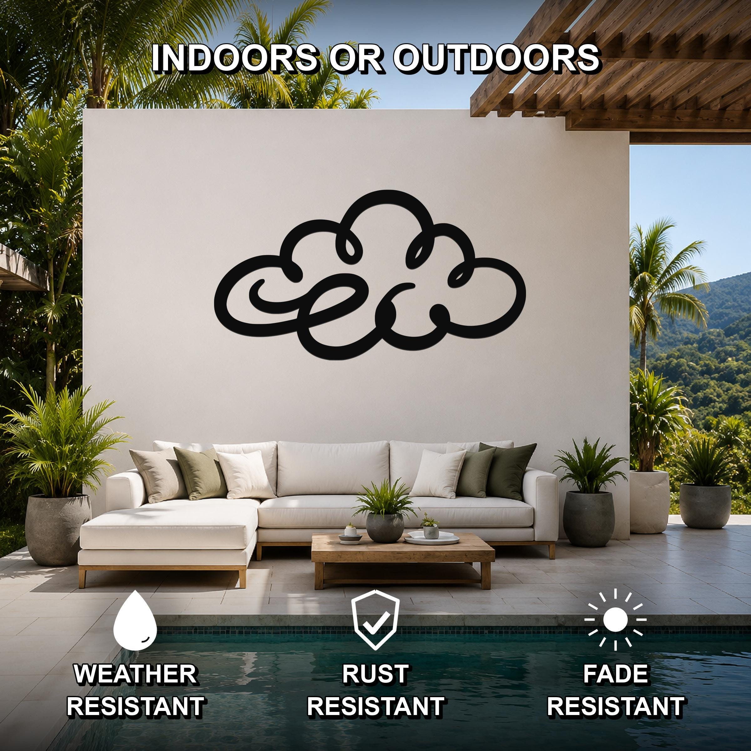 Black metal cloud wall art with internal cutout details, mounted on a white outdoor wall above a white sectional sofa in a patio living area.