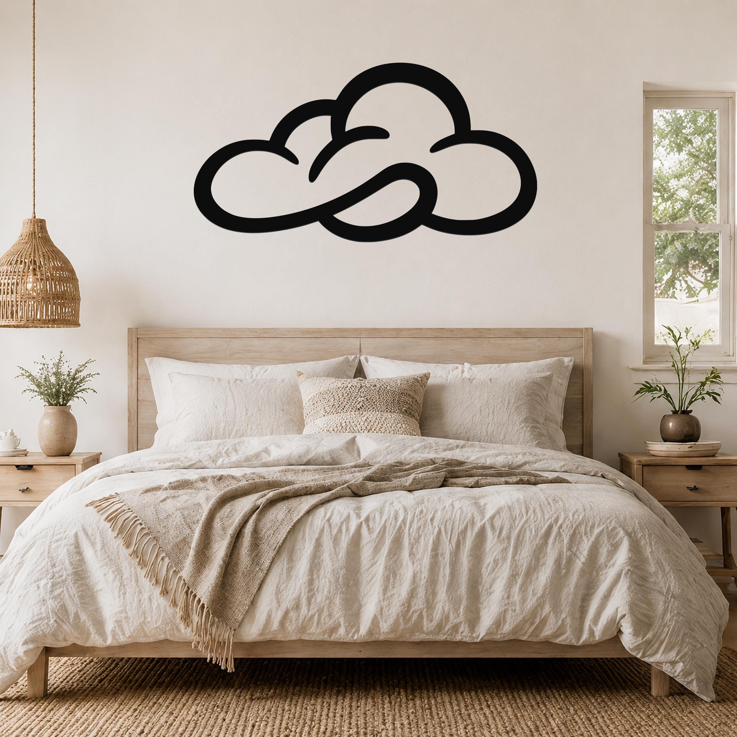 Black metal cloud wall art with open silhouette design, mounted above a wooden bed in a neutral bedroom.