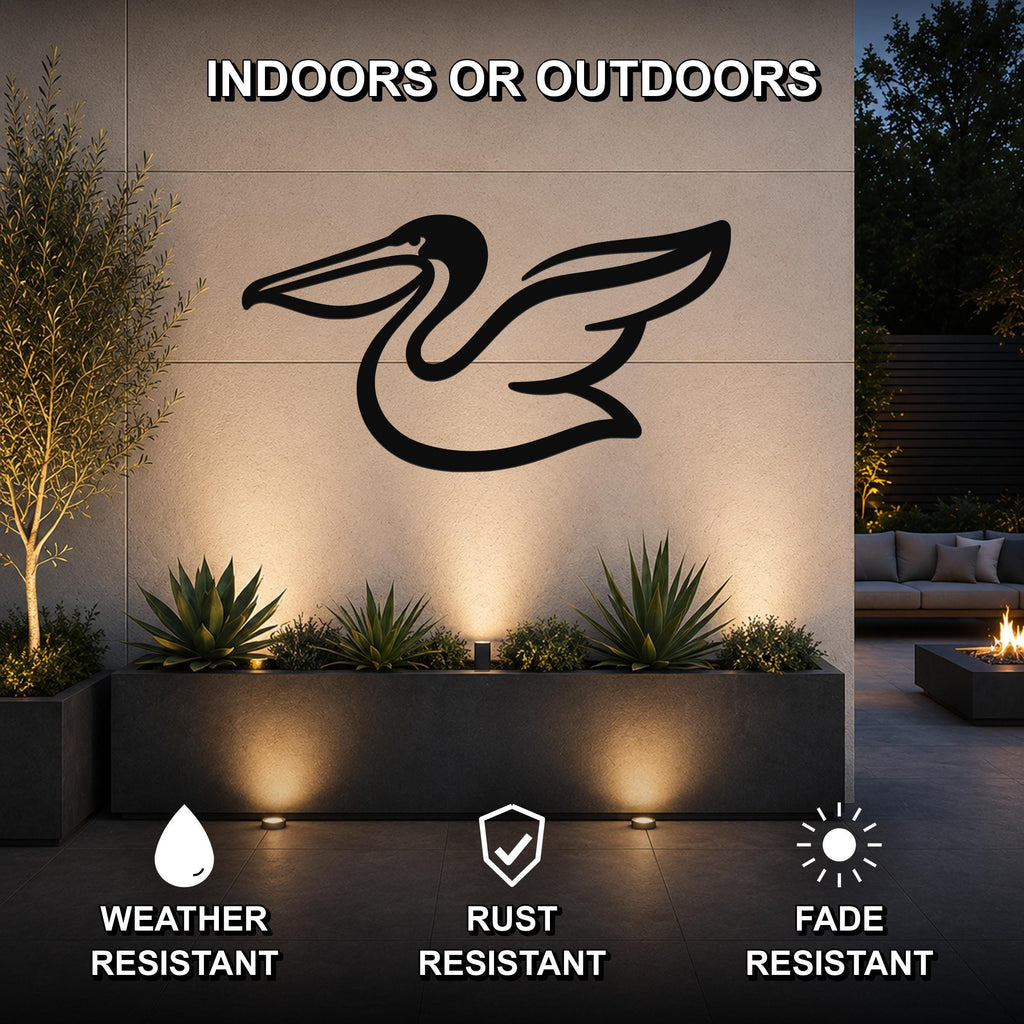 Black metal pelican wall art with wing and neck cutouts, mounted on an outdoor wall above a planter in a patio setting.