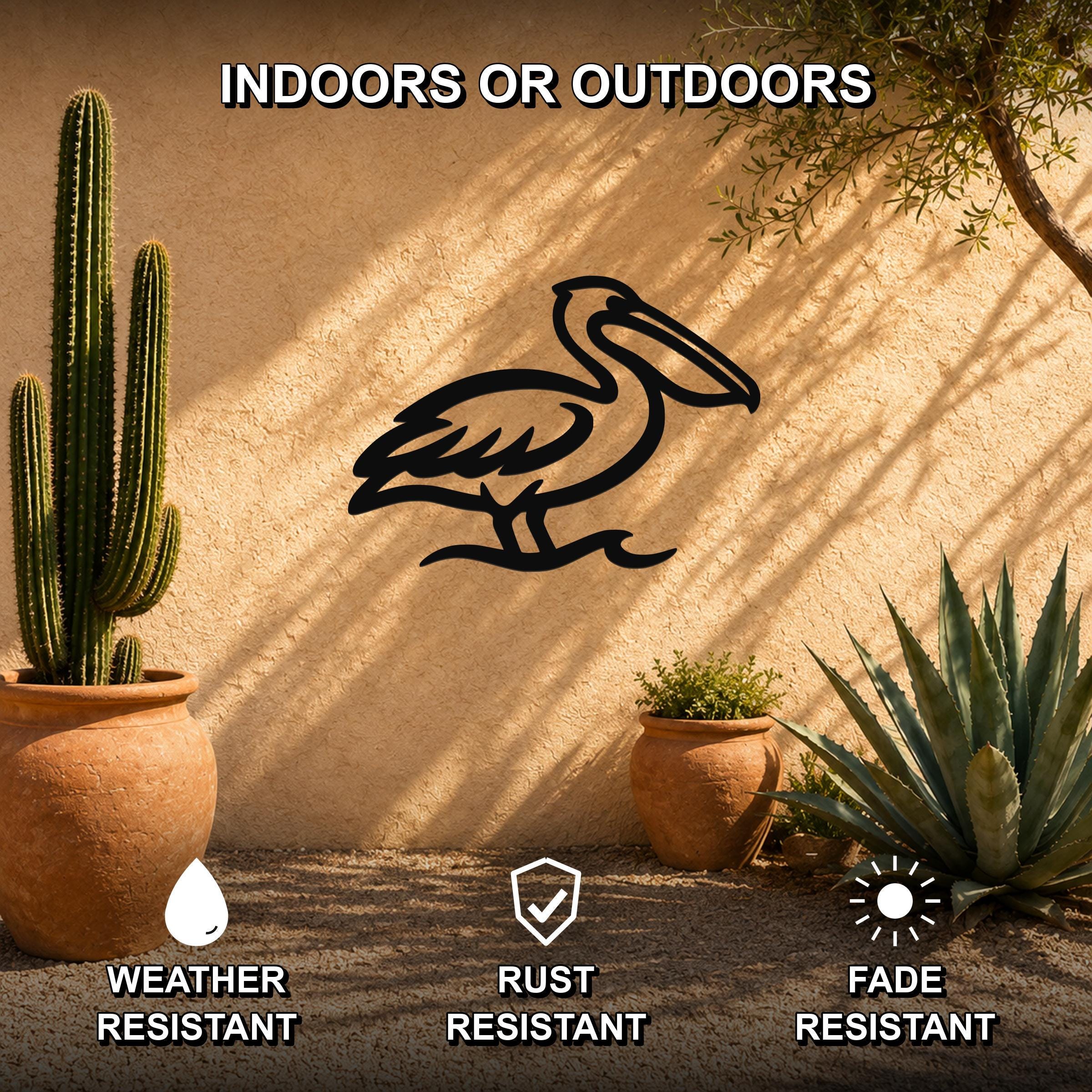 Black metal pelican wall art silhouette mounted on a stucco outdoor wall, surrounded by potted cacti and succulents in a sunlit patio setting.