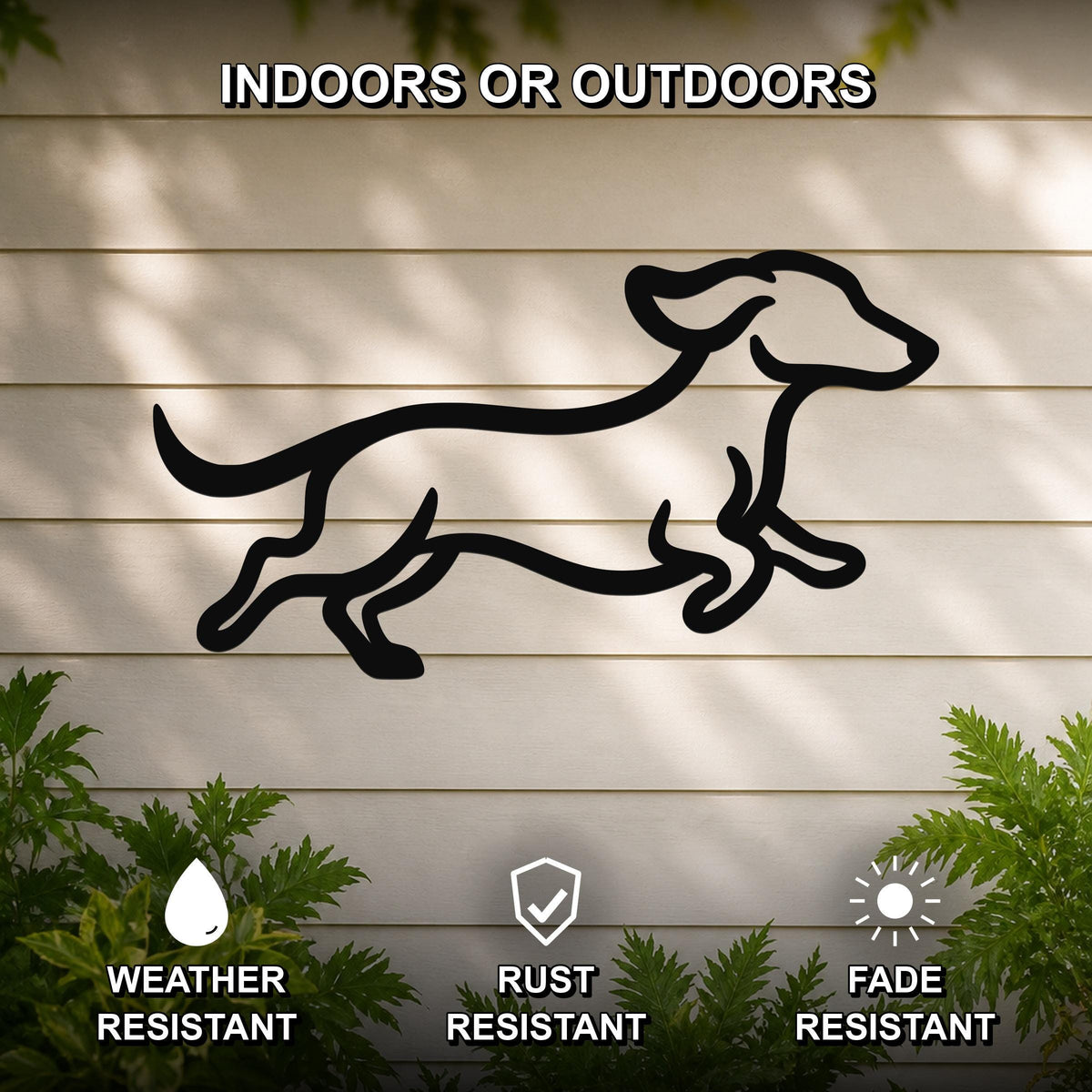 Black metal dachshund wall art in a running silhouette, mounted on a light-colored outdoor wall with greenery, weather, rust, and fade resistant.