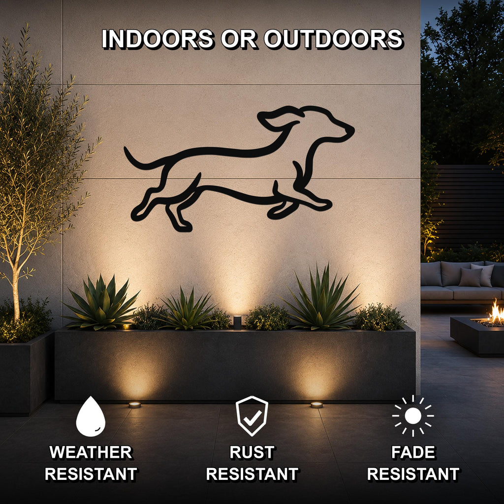 Black metal dachshund wall art with a running silhouette, mounted on an outdoor wall above a planter in a modern patio setting.