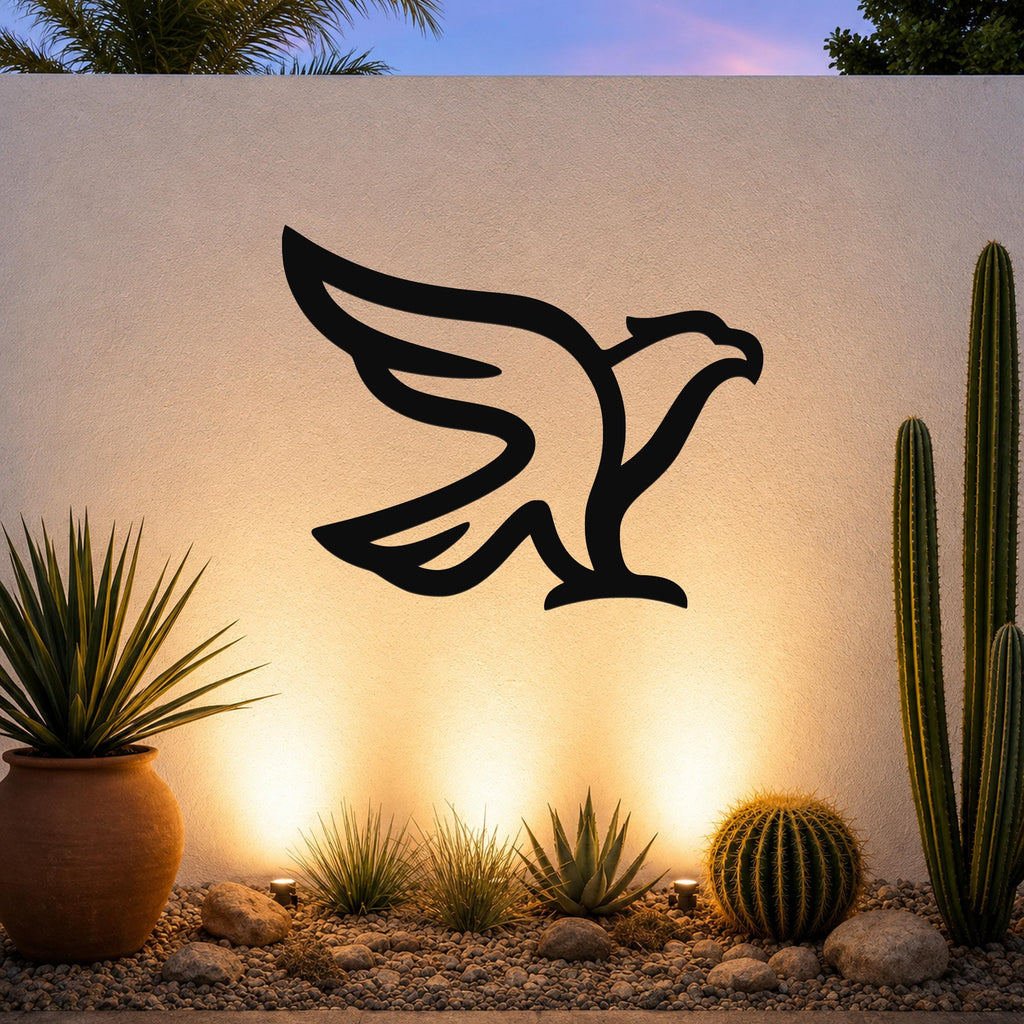 Black metal eagle wall art with a bold silhouette design, mounted on an outdoor wall above a desert garden with cacti and warm uplighting.