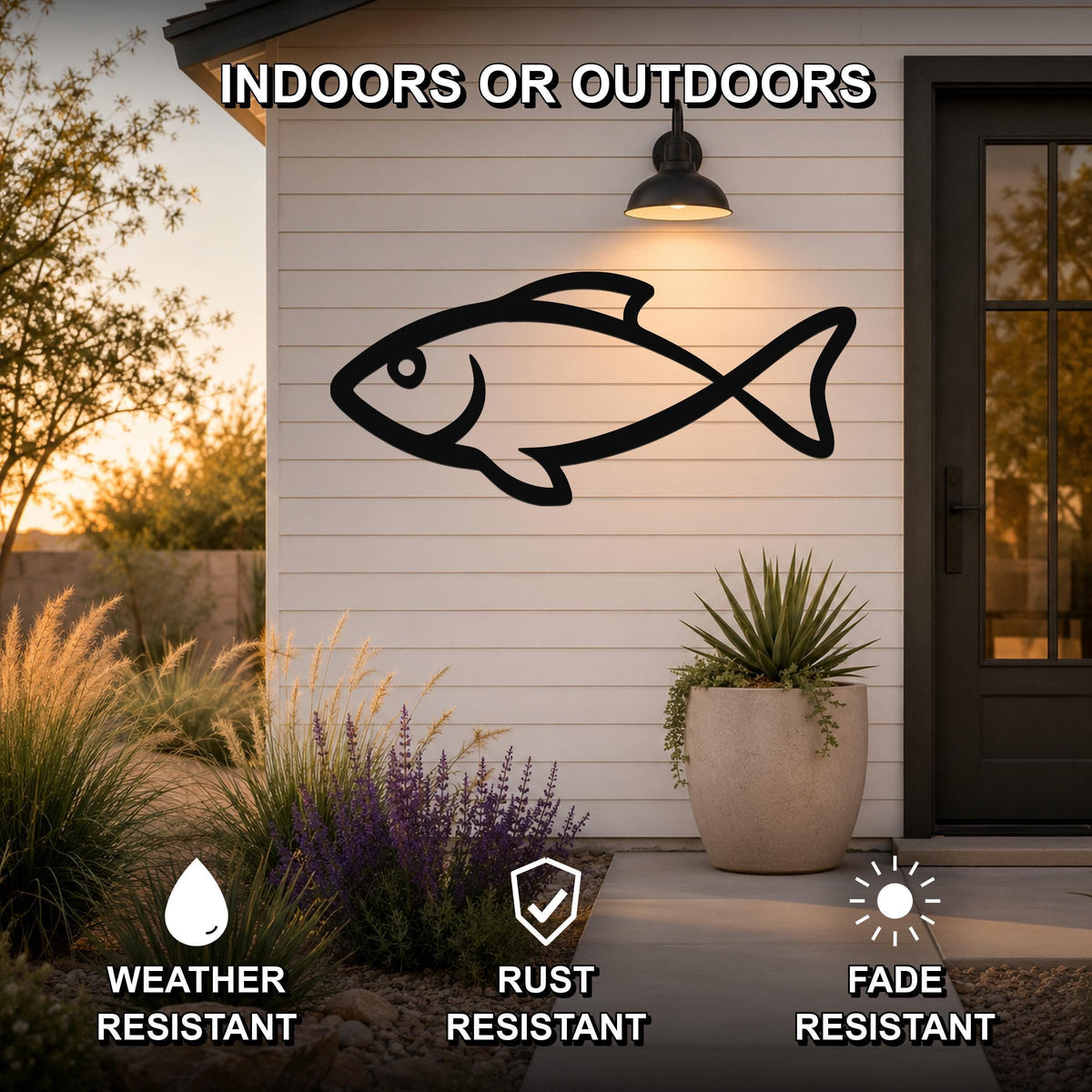 Black metal fish silhouette wall art mounted on a white outdoor wall beside a door, with text indicating it is weather, rust, and fade resistant.