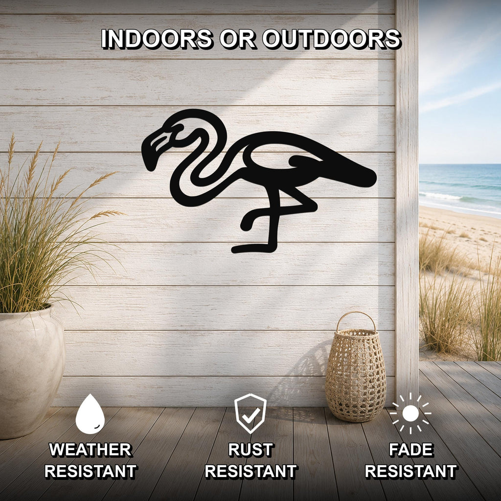 Black metal flamingo wall art silhouette mounted on a light wood plank wall, displayed on a patio with a beach view, weather resistant, rust resistant, and fade resistant.