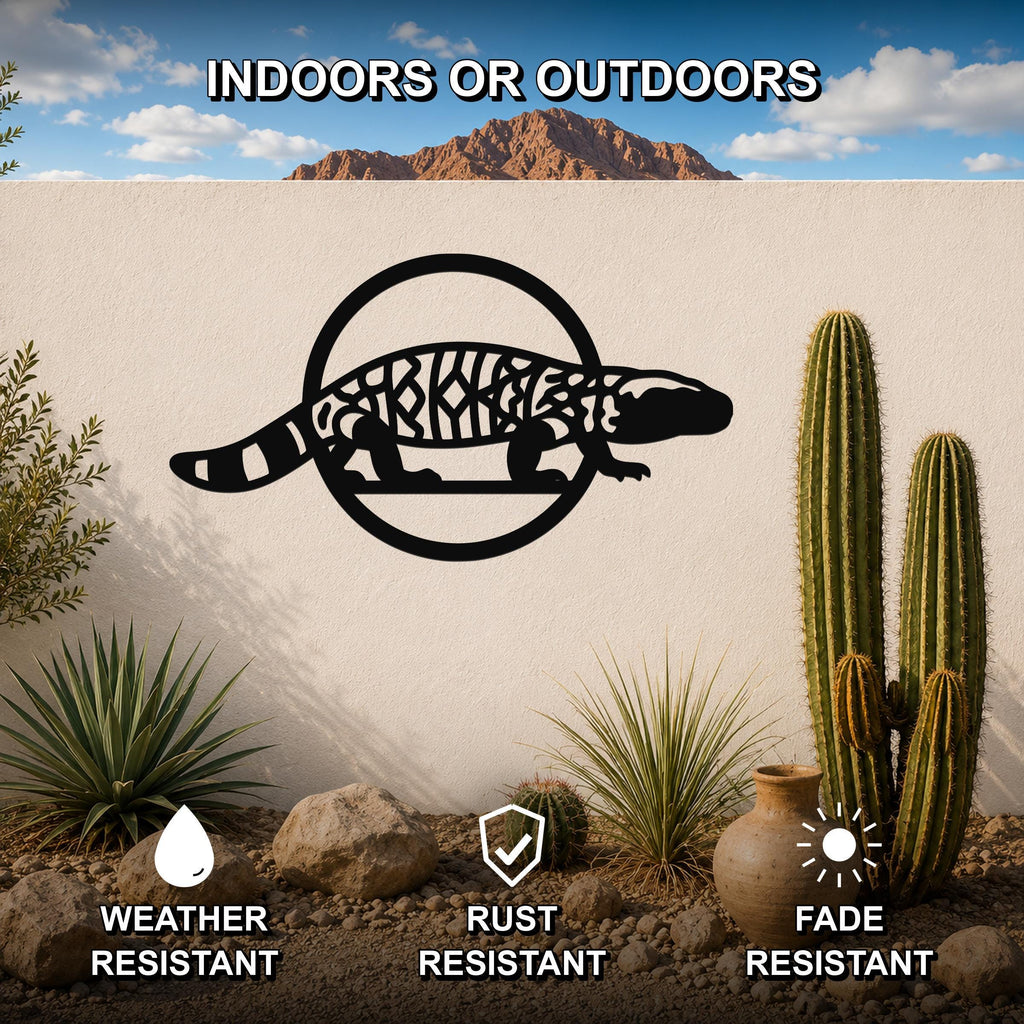 Black metal Gila monster wall art with intricate internal cutouts, mounted on a white outdoor wall in a desert garden setting.
