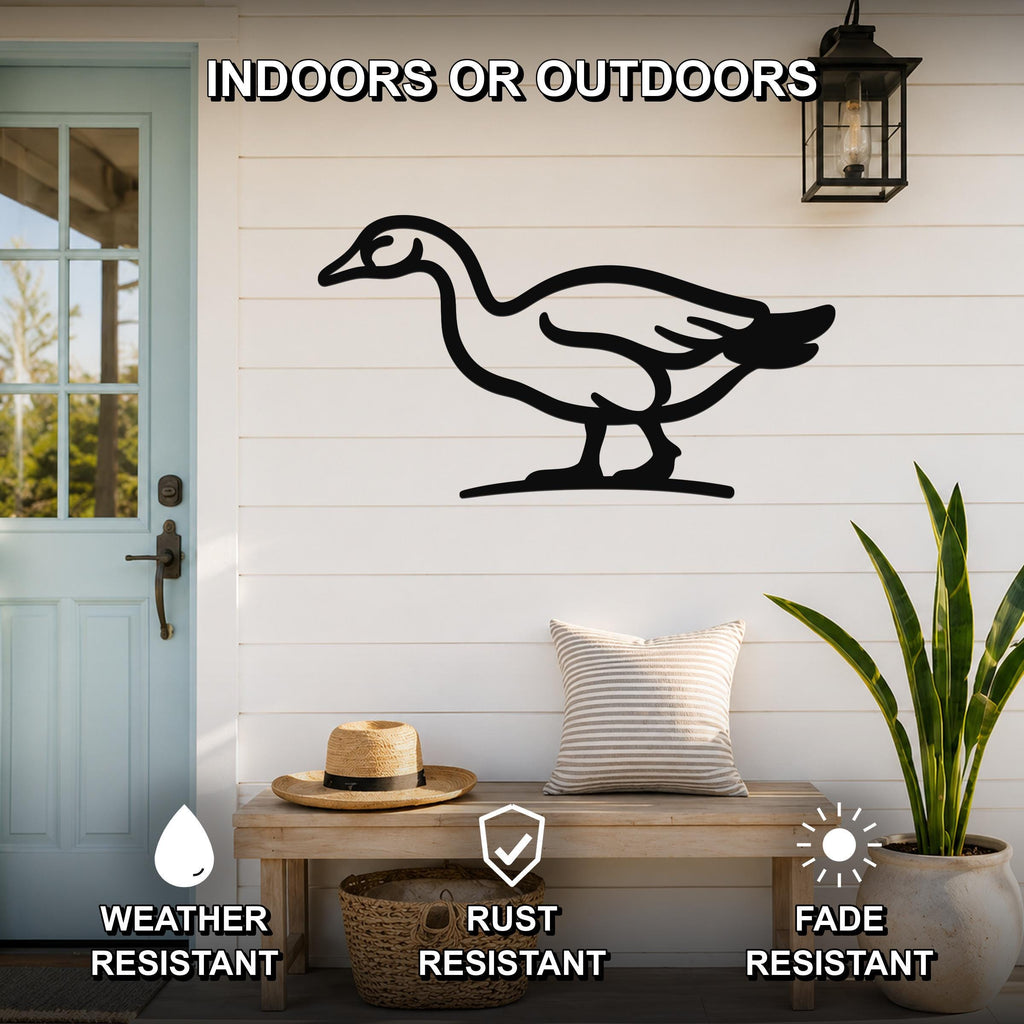 Black metal goose wall art silhouette mounted on a white shiplap wall above a wooden bench in a porch setting.