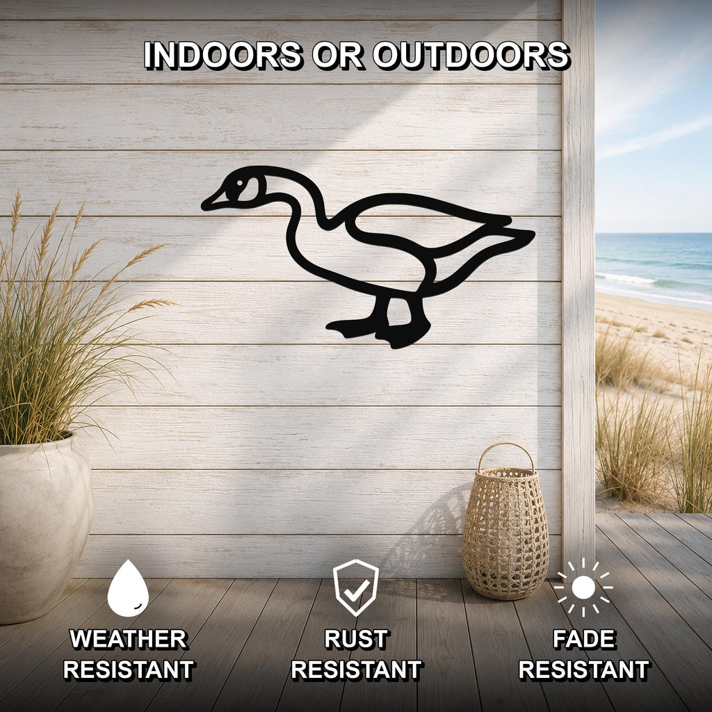Black metal goose silhouette wall art mounted on a light wood plank wall, shown in an indoor-outdoor setting with a beach view, weather resistant, rust resistant, and fade resistant.