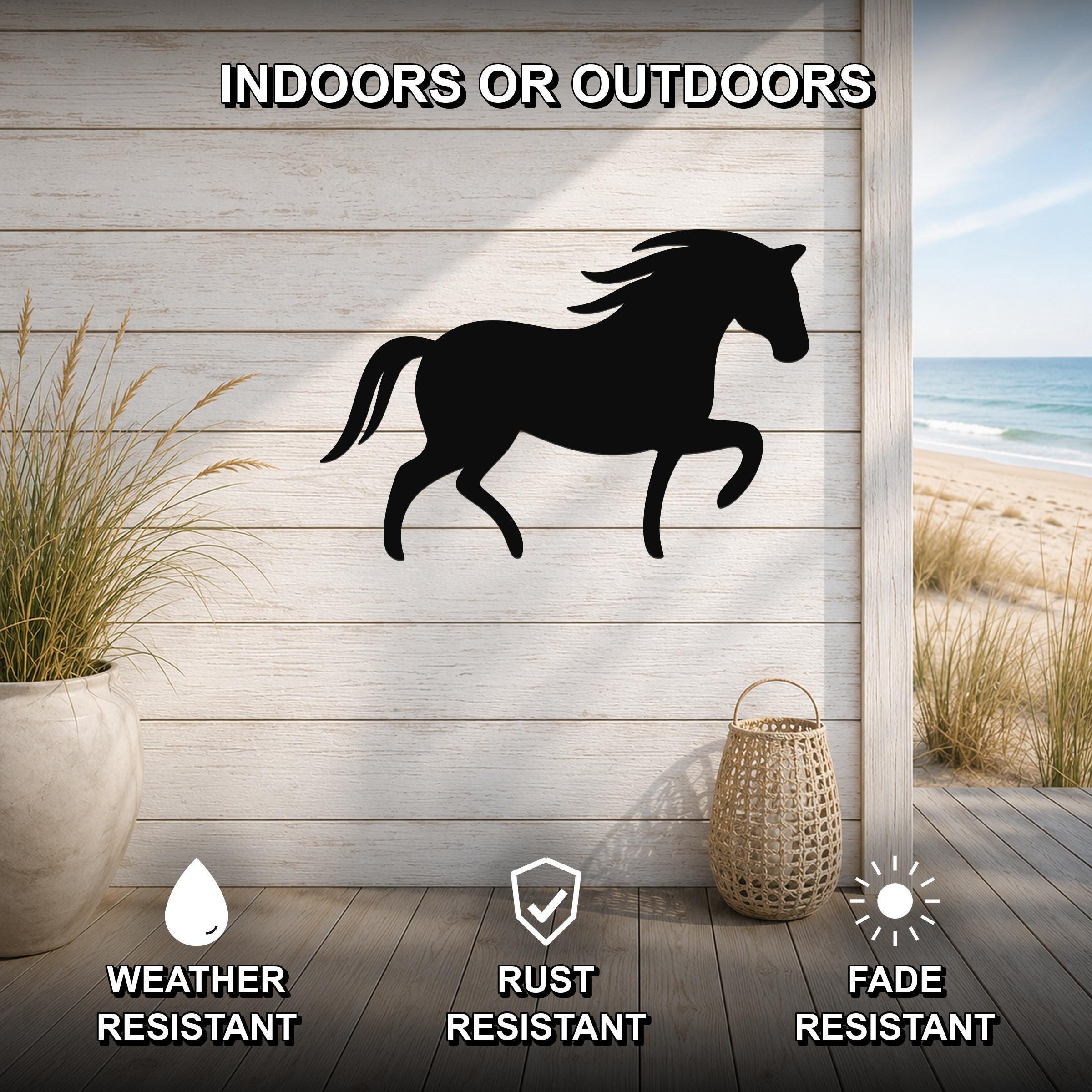 Black metal horse silhouette wall art mounted on a light wood plank wall, displayed on a patio with a beach view, weather resistant, rust resistant, and fade resistant.