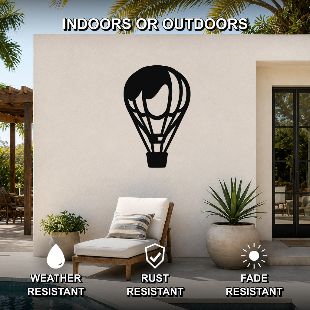 Black metal hot air balloon wall art with internal cutout details, mounted on an outdoor patio wall above a lounge chair.