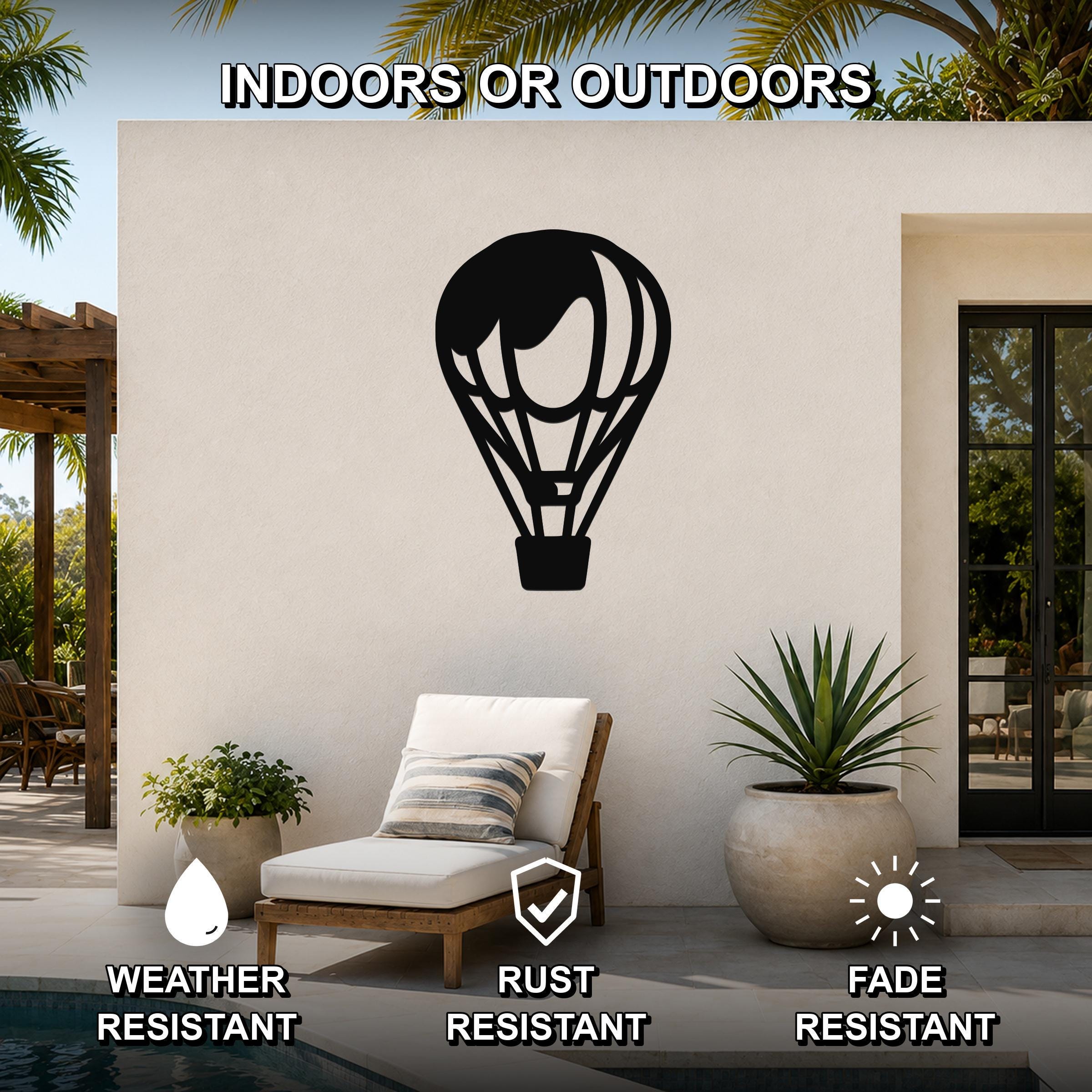 Black metal hot air balloon wall art with internal cutout details, mounted on an outdoor patio wall above a lounge chair.