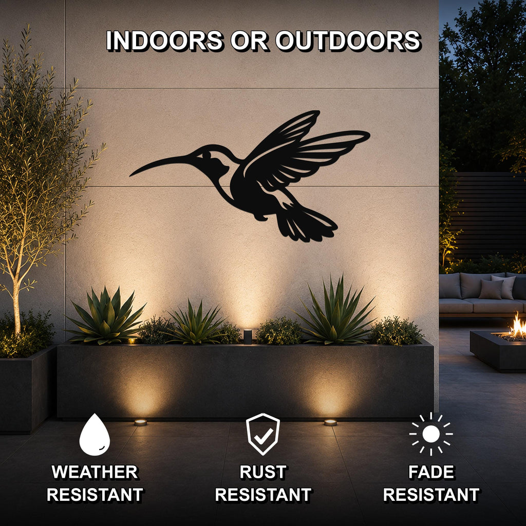 Black metal hummingbird wall art with an airy silhouette design, mounted on an outdoor wall above a planter in a modern patio setting.