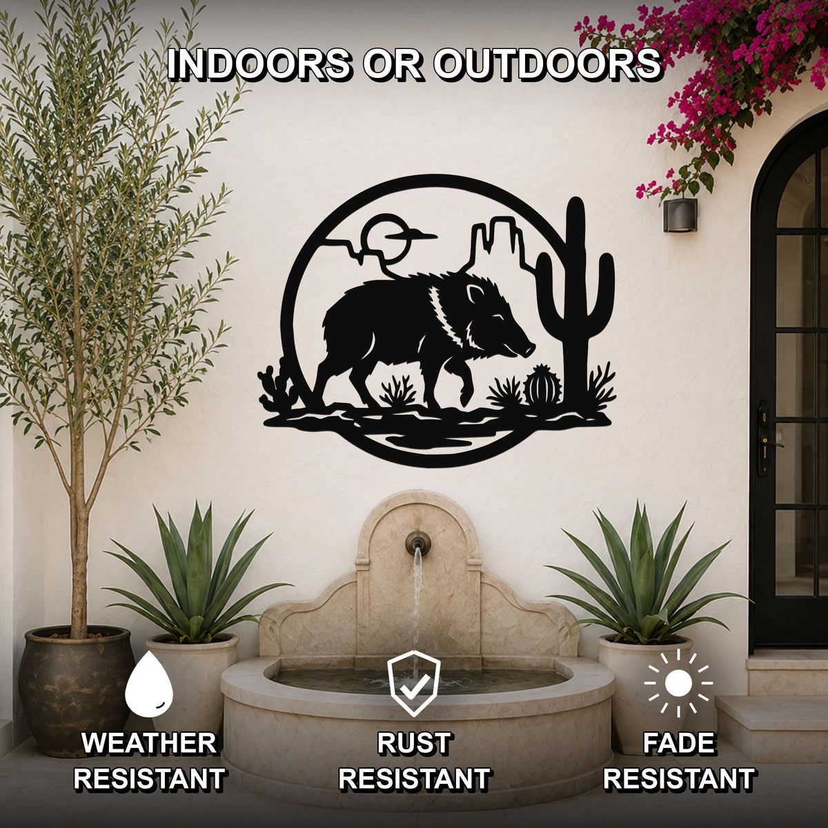 Black metal wall art featuring a javelina silhouette with cactus and desert landscape cutouts, mounted on an outdoor patio wall above a stone fountain.