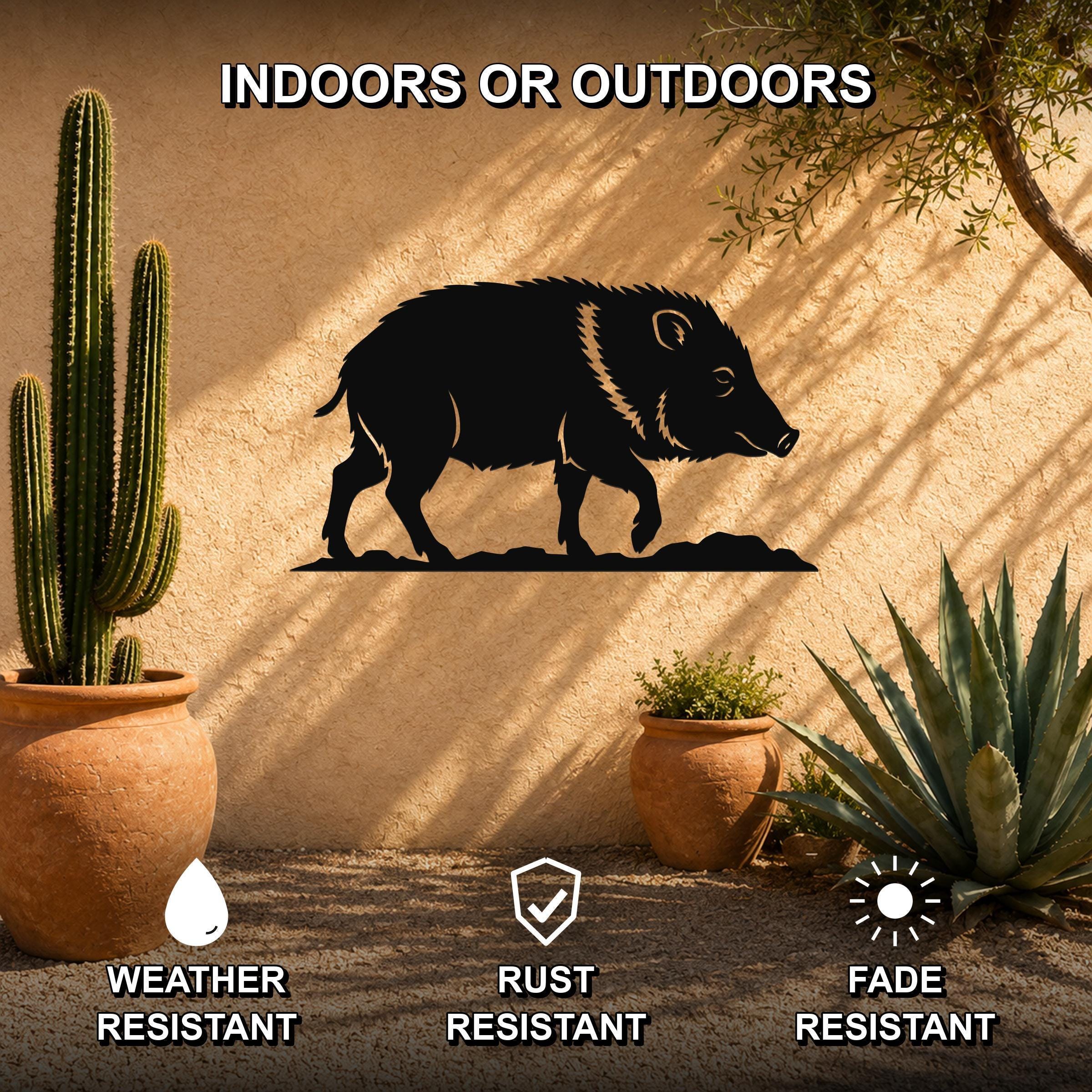 Black metal javelina wall art silhouette mounted on an outdoor stucco wall, surrounded by potted cacti and succulents in a desert-style patio setting.