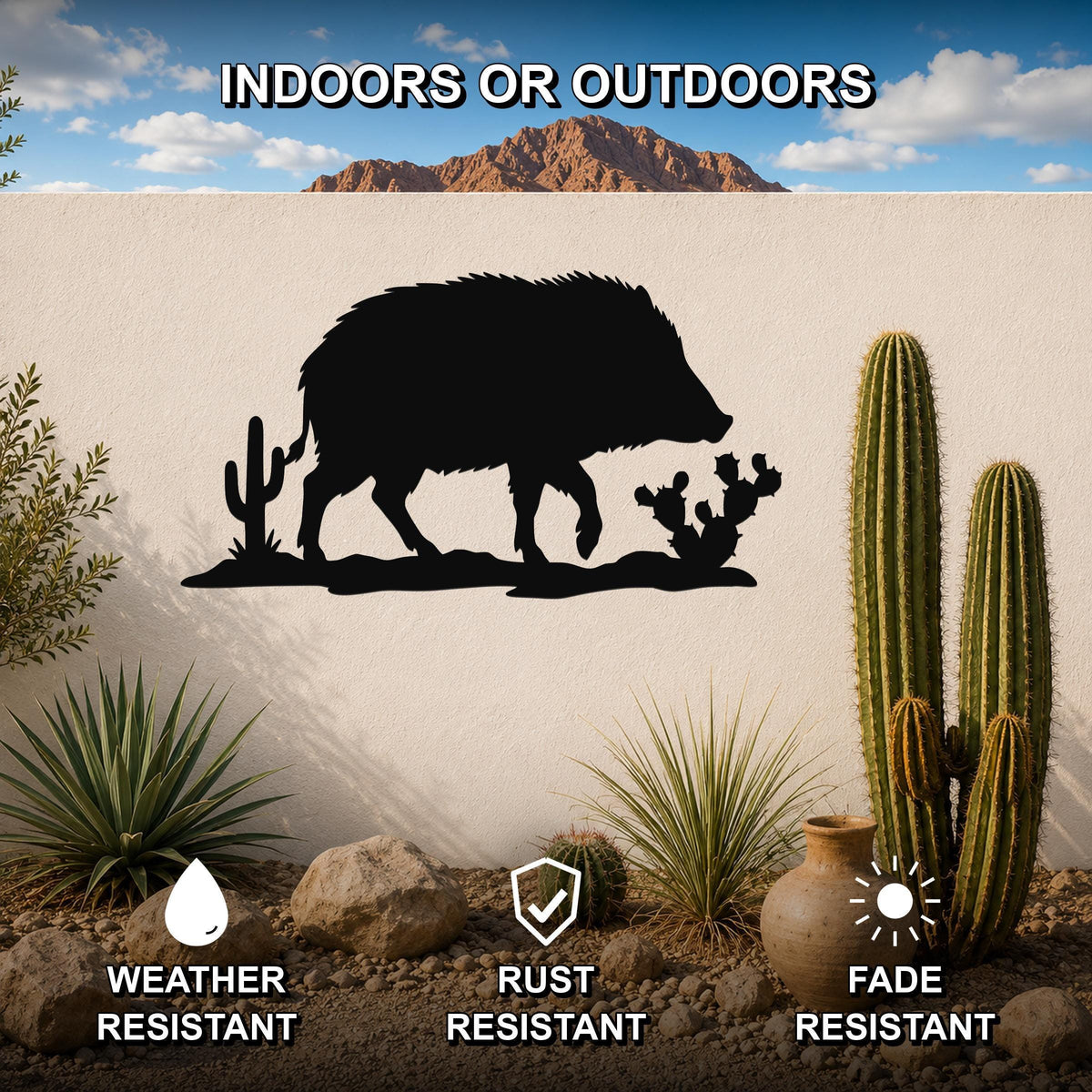 Black metal javelina wall art silhouette with cactus cutouts, mounted on an outdoor wall in a desert landscape setting.