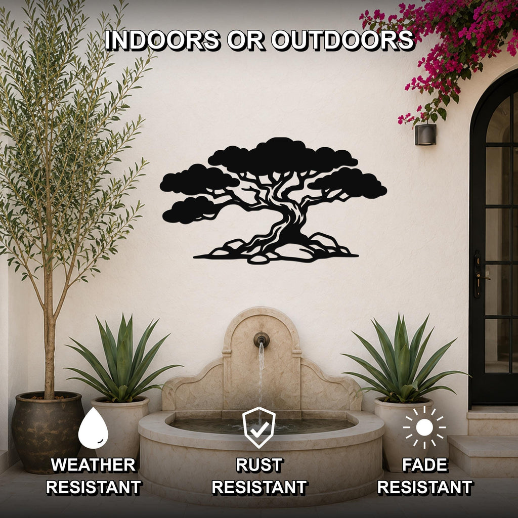Black metal juniper tree wall art with wind-sculpted silhouette, mounted on an outdoor wall above a stone fountain in a patio setting.