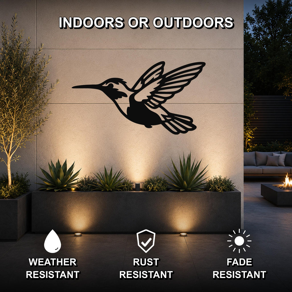 Black metal hummingbird wall art with wing and tail cutouts, mounted on an outdoor wall above a planter in a patio setting.