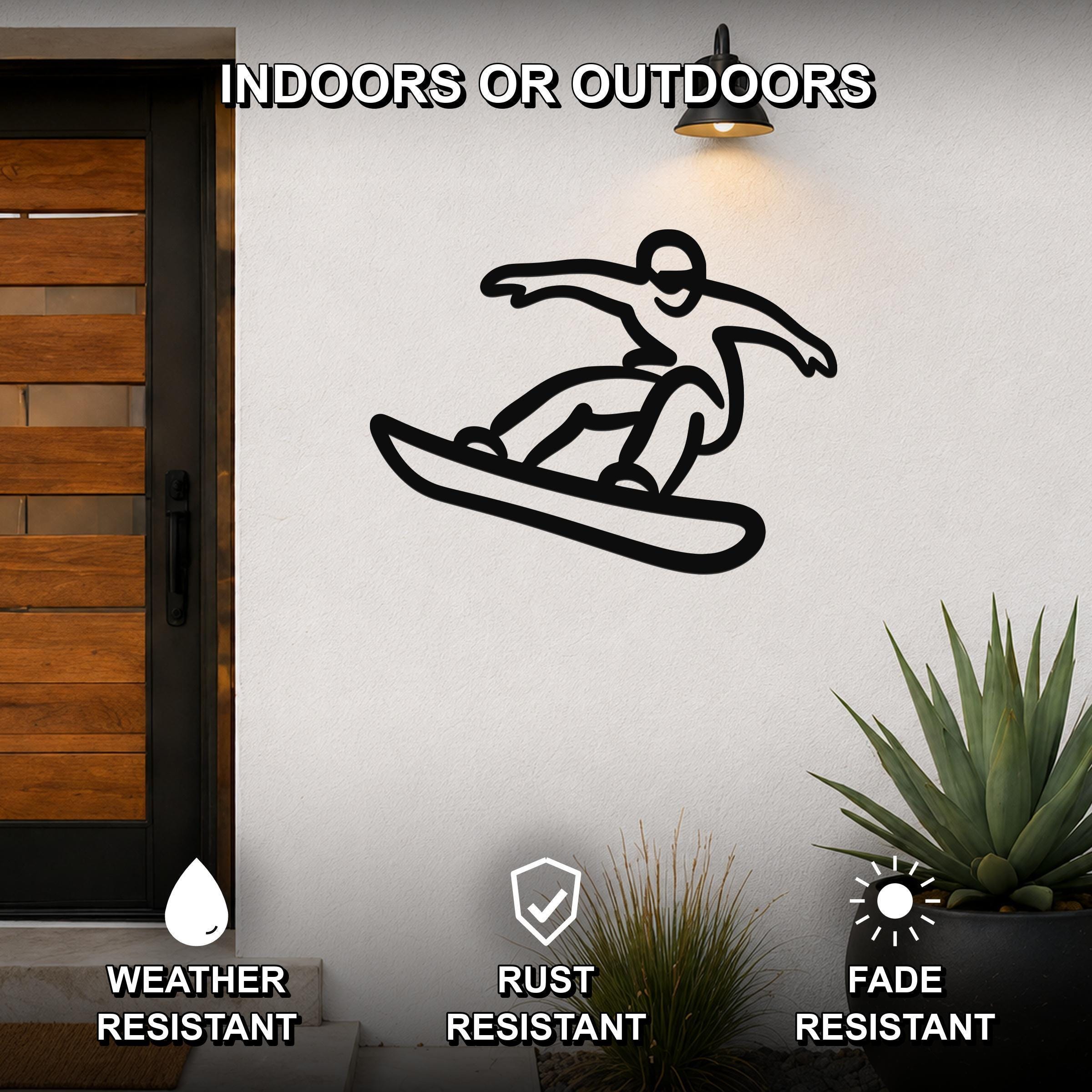 Black metal wall art silhouette of a snowboarder in motion, mounted on an outdoor wall beside a wooden door and potted plants.