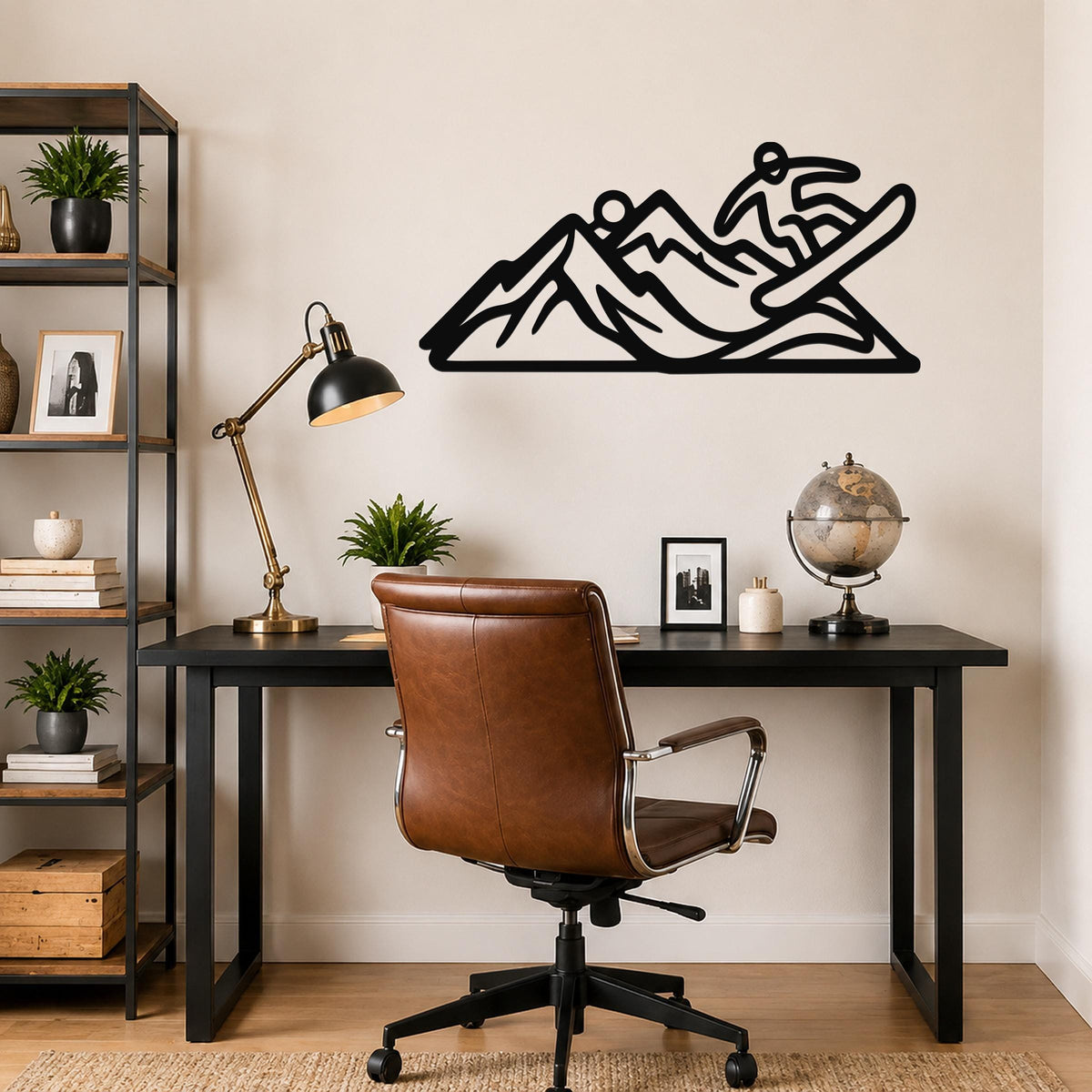 Black metal wall art silhouette of a snowboarder in motion over mountain peaks, mounted above a black desk in a home office.