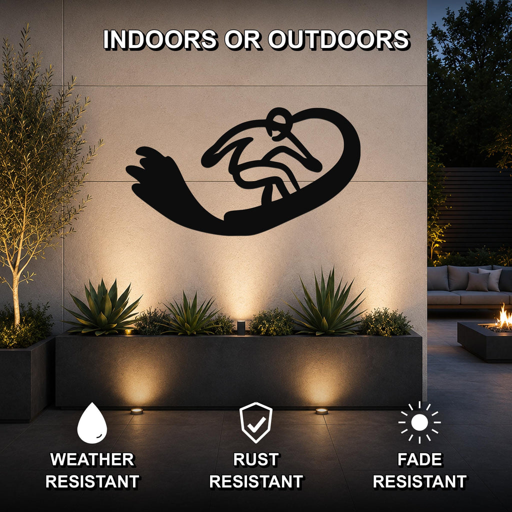 Black metal wall art of a snowboarder silhouette with motion lines, mounted on an outdoor wall above a planter in a modern patio setting.