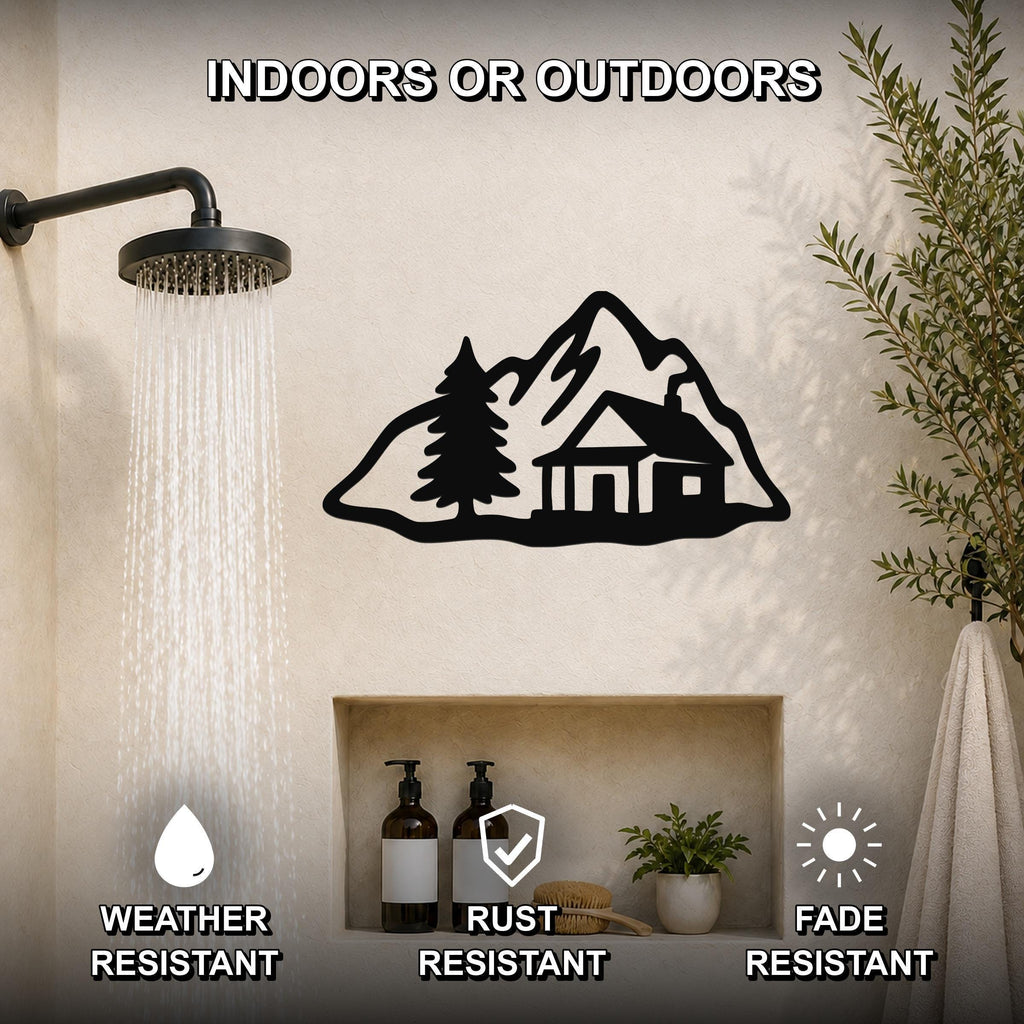 Black metal wall art featuring a mountain cabin silhouette with a pine tree, mounted on a bathroom wall above a built-in shelf, shown near a running showerhead.