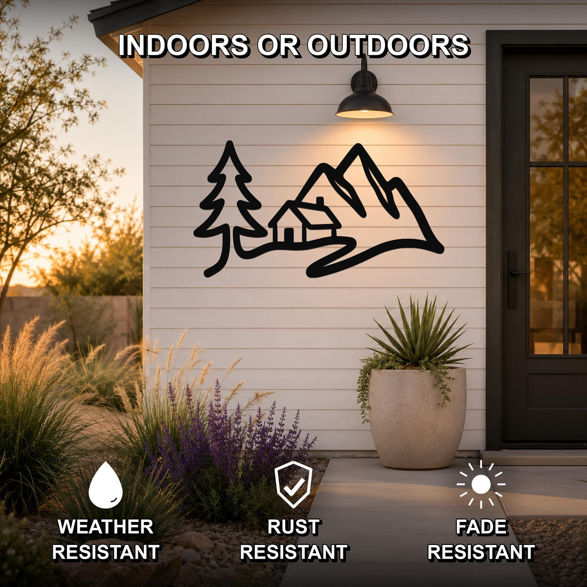 Black metal wall art with a mountain cabin silhouette design, mounted on a white exterior wall beside a door, featuring weather, rust, and fade resistance.