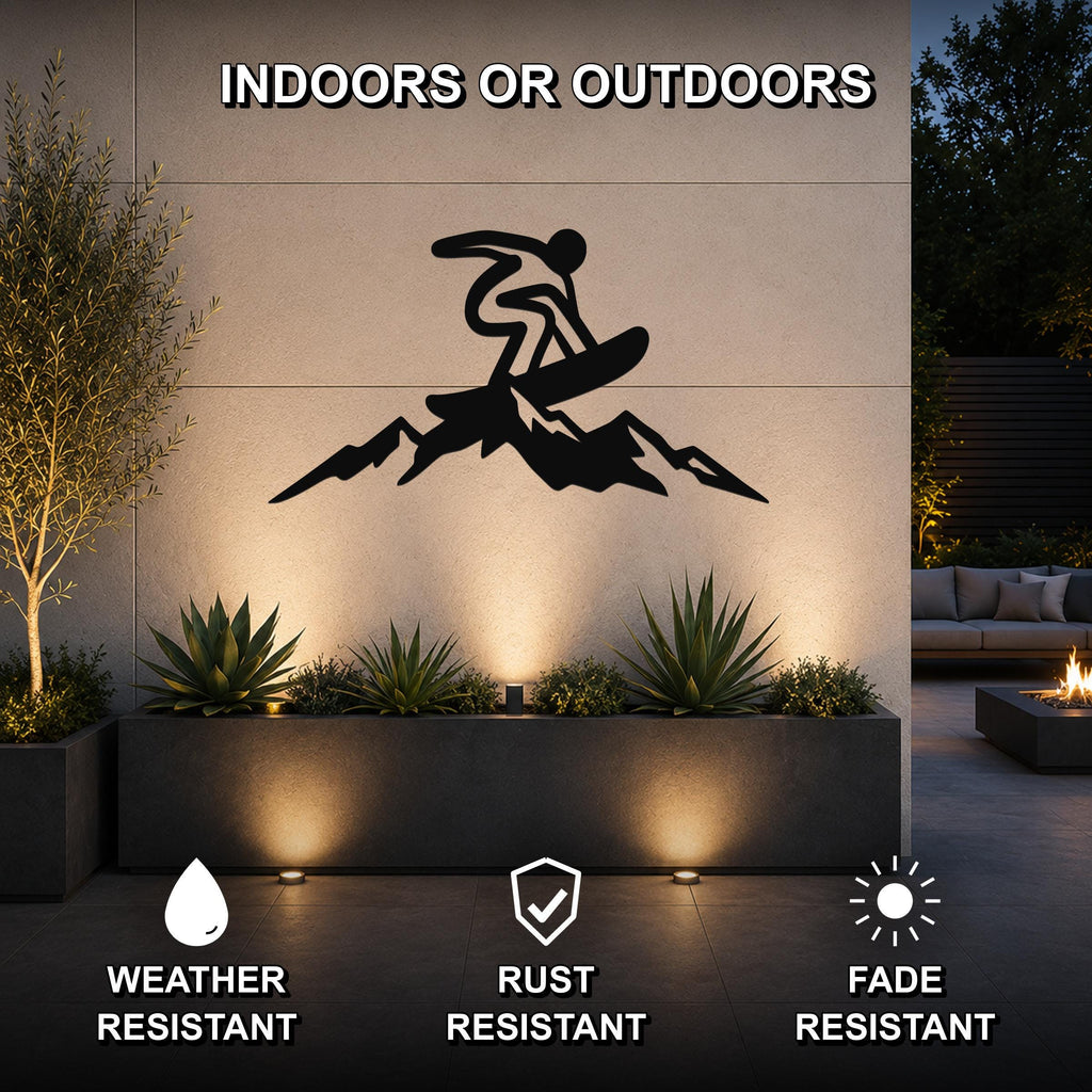 Black metal wall art featuring a snowboarder silhouette above mountain peaks, mounted on an outdoor wall above a planter in a modern patio setting.