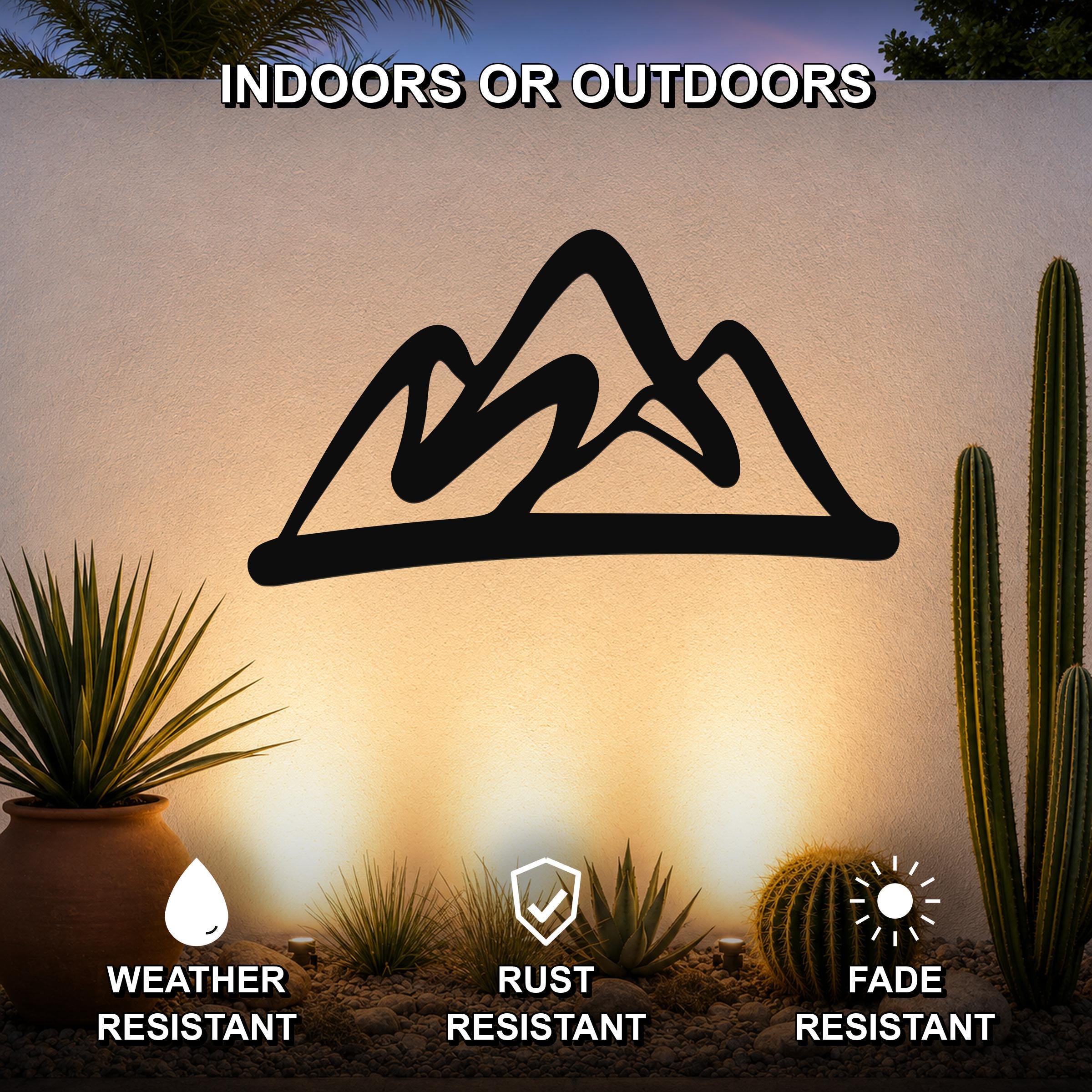 Black metal mountain silhouette wall art mounted on an outdoor wall above a desert garden with cacti, featuring weather, rust, and fade resistance.