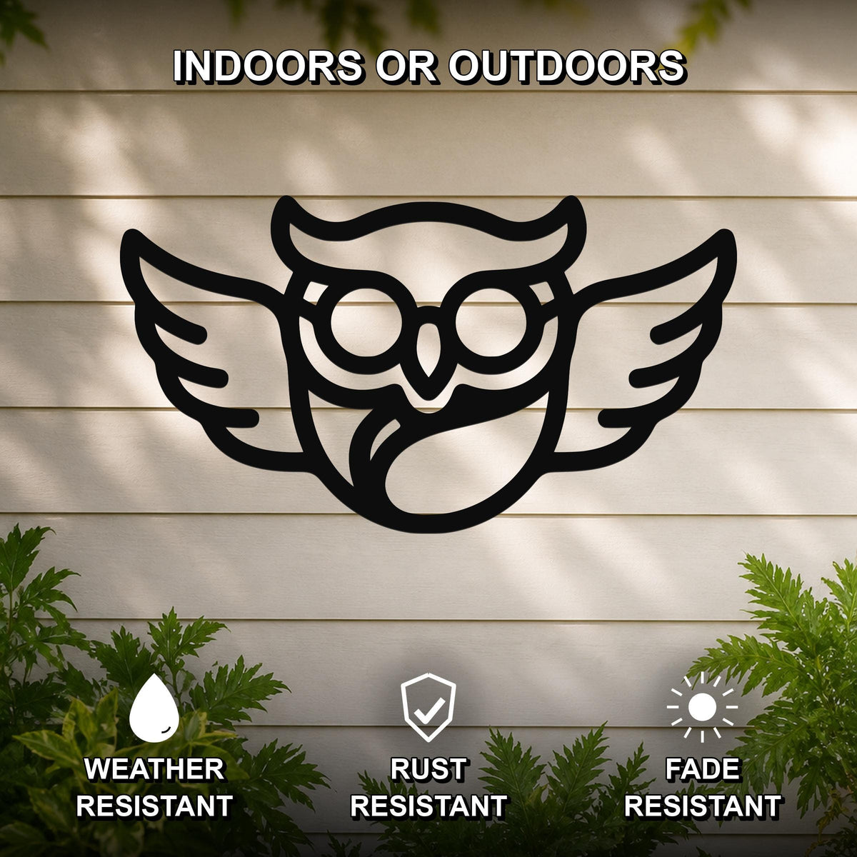 Black metal silhouette wall art of a bespectacled owl with outstretched wings, mounted on a light-colored outdoor wall with greenery below.