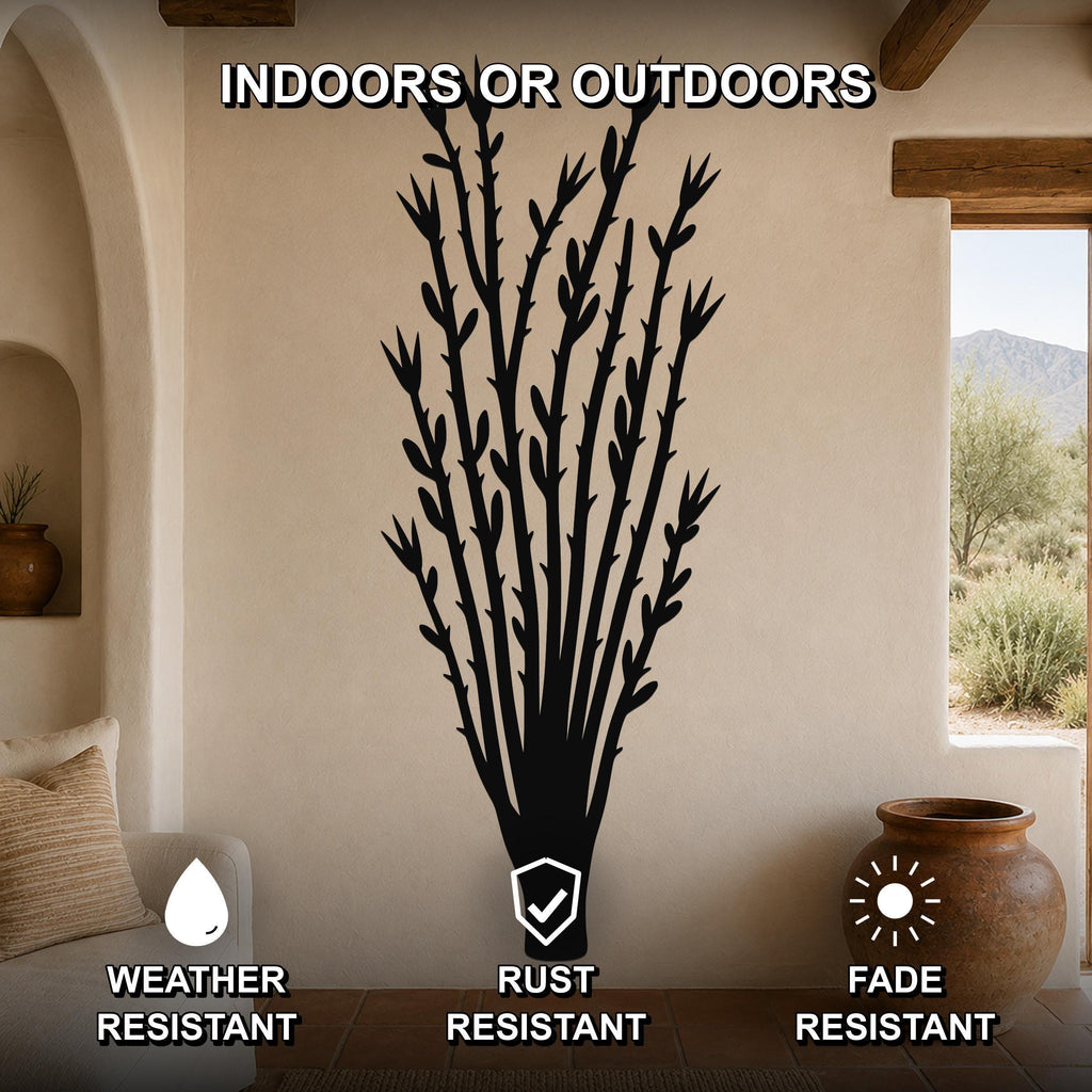Black metal ocotillo wall art with branch and leaf cutouts, mounted on a beige living room wall above a sofa, shown with weather, rust, and fade resistance icons.
