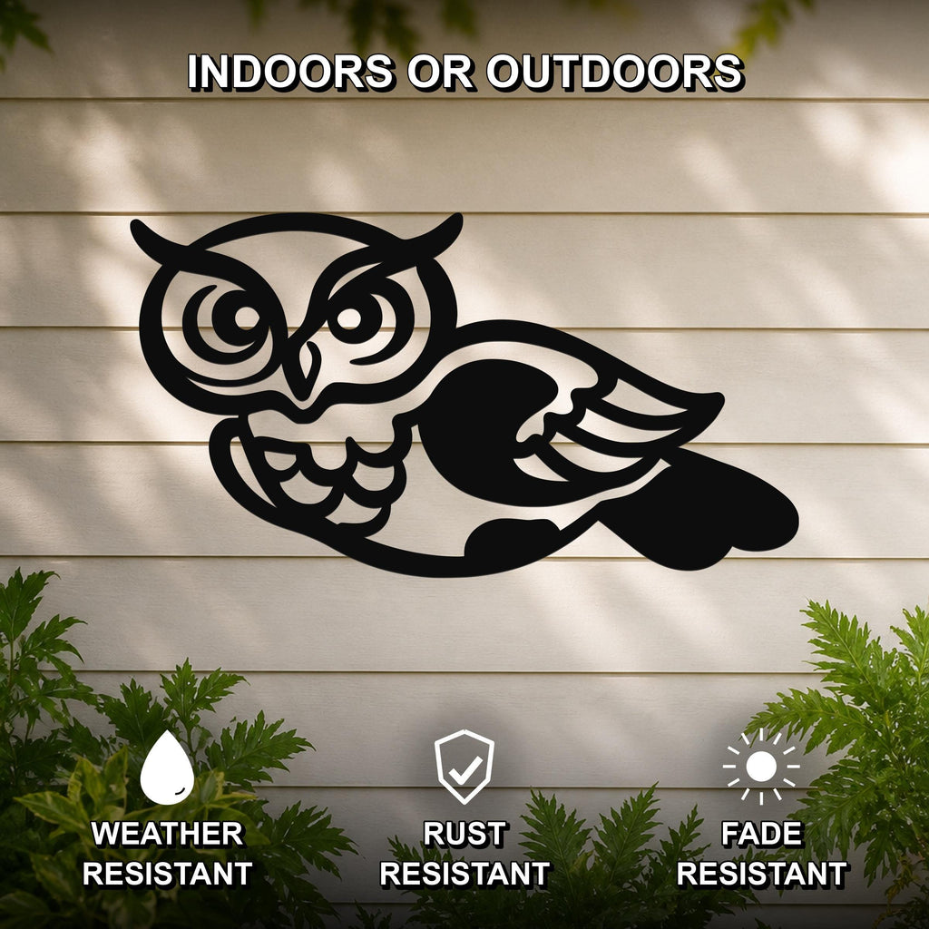 Black metal owl wall art with cutout details, mounted on a light-colored outdoor wall with greenery below.