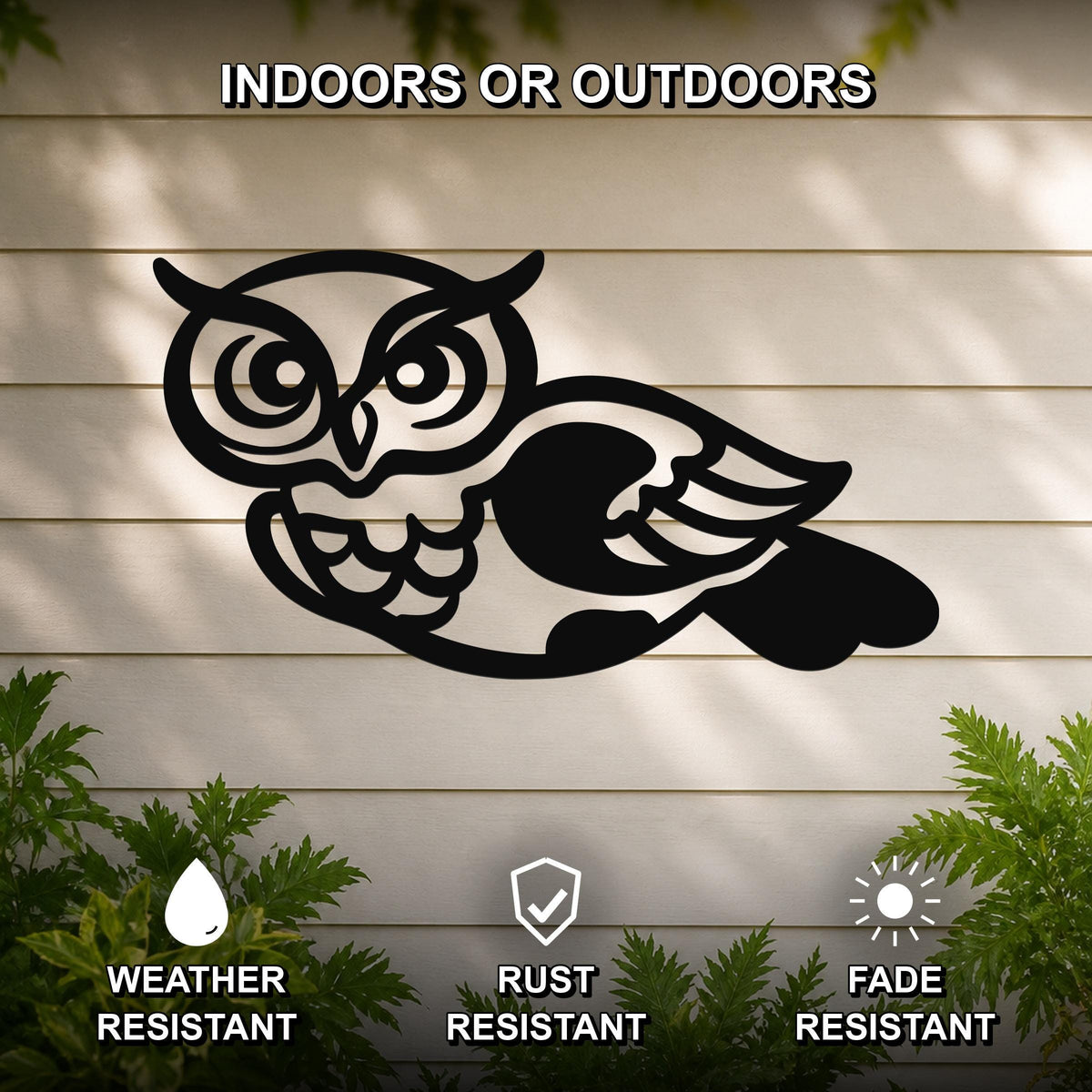 Black metal owl wall art with cutout details, mounted on a light-colored outdoor wall with greenery below.