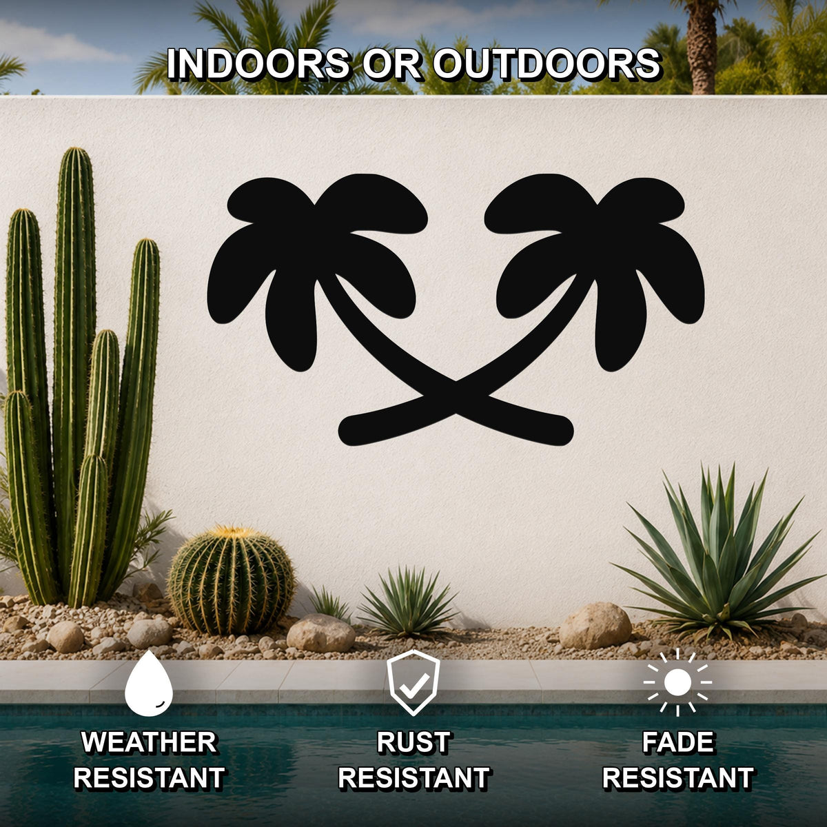 Black metal palm tree wall art with crossed trunks and frond silhouettes, mounted on an outdoor wall above a pool in a desert garden setting.