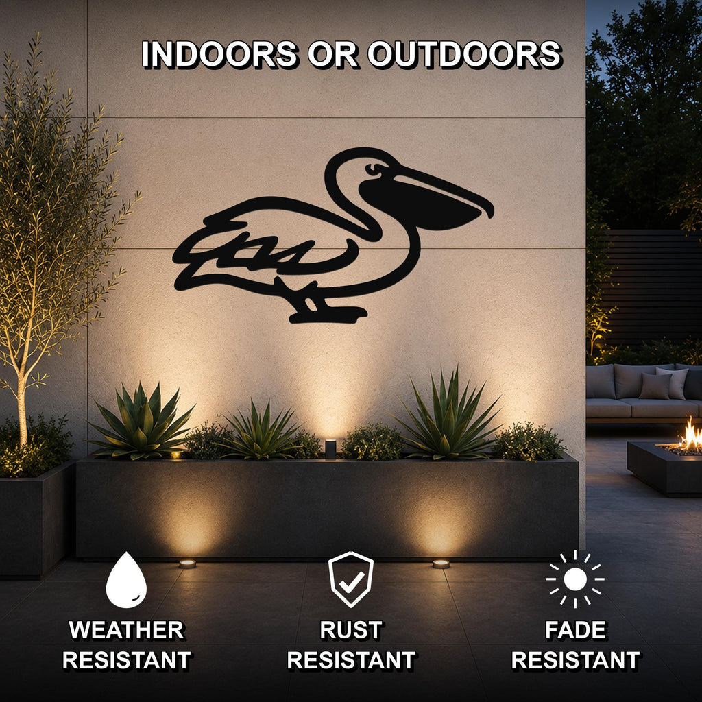 Black metal pelican wall art silhouette mounted on an outdoor wall above a planter, illuminated by uplights in a modern patio setting.