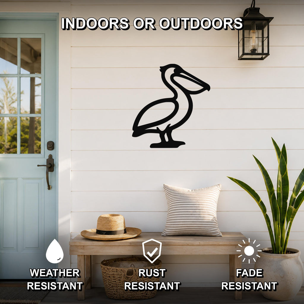 Black metal pelican wall art silhouette mounted on a white shiplap wall above a wooden bench in a coastal entryway.